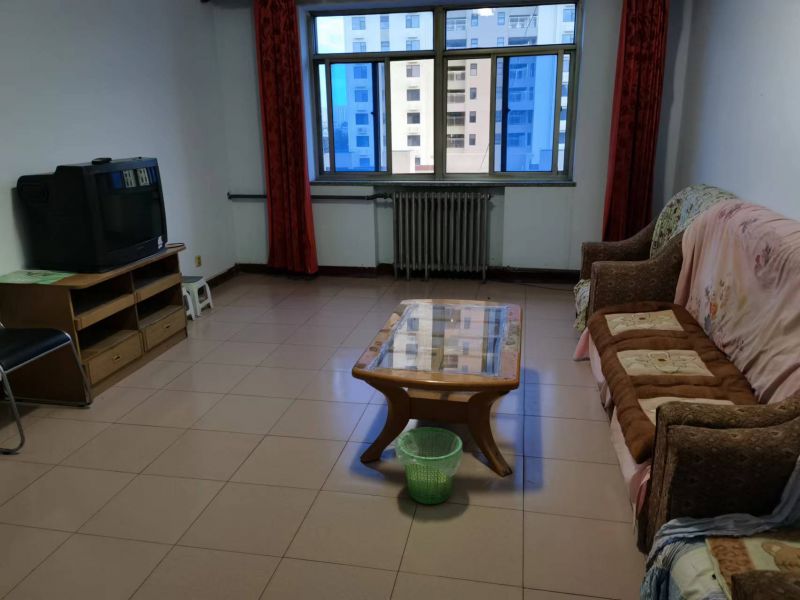 客厅空间，地面铺设米色瓷砖，配有电视柜和沙发。房间采光适中，整体装修风格偏基础实用型。