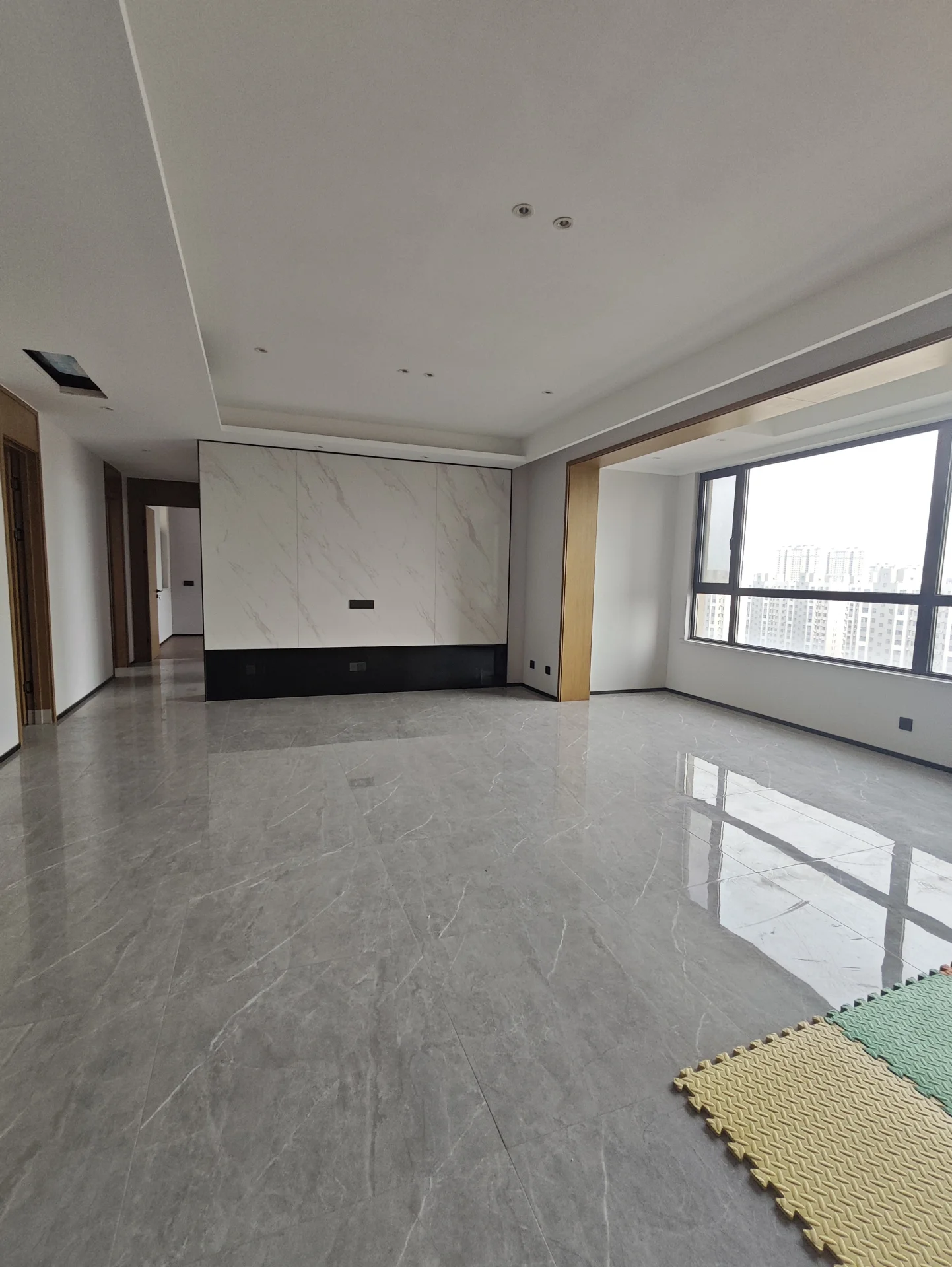 宽敞明亮的房间，白墙白地，两扇窗户引入自然光。地毯增添温暖舒适感，整体干净整洁，营造出温馨的氛围。关键字:宽敞 明亮 白墙 自然光 地毯 温暖舒适 干净整洁