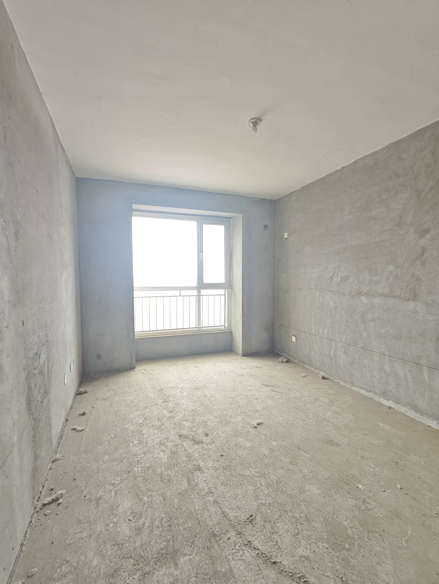 宽敞明亮的房间，大窗户带来充足自然光。混凝土墙面简洁，透露出施工或刚装修的痕迹。空旷静谧，适合 loft 或各种活动空间，工业风格增添独特魅力。关键字:宽敞明亮 大窗户 自然光 混凝土墙面 工业风格 loft