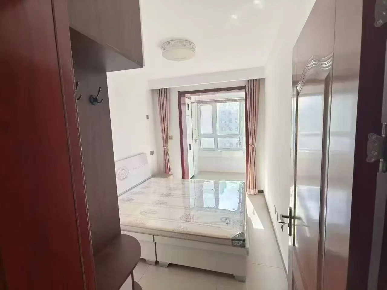 小而干净的房间，白色墙壁和木质地板营造出宁静优雅的氛围。床置于中央，两侧各有一张夜桌。两扇窗户分别位于两侧，自然光洒满房间。目前看来空无一人，整体给人一种平静舒适的感觉。关键字:小房间 白色墙壁 木质地板 床 夜桌 窗户 自然光 宁静优雅