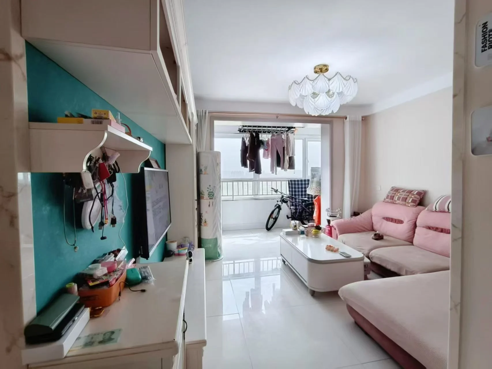 宽敞明亮的客厅，白色瓷砖地面，中央摆放大沙发和两把椅子，三扇窗户自然采光。电视墙挂，中心有餐桌。装饰包括窗边盆栽、两尊花瓶和三个瓶子，沙发旁可见手提包。整体氛围舒适宜人，注重整洁与有序。关键字:宽敞明亮 白色瓷砖 大沙发 椅子 自然采光 电视墙挂 餐桌 盆栽 花瓶 手提包