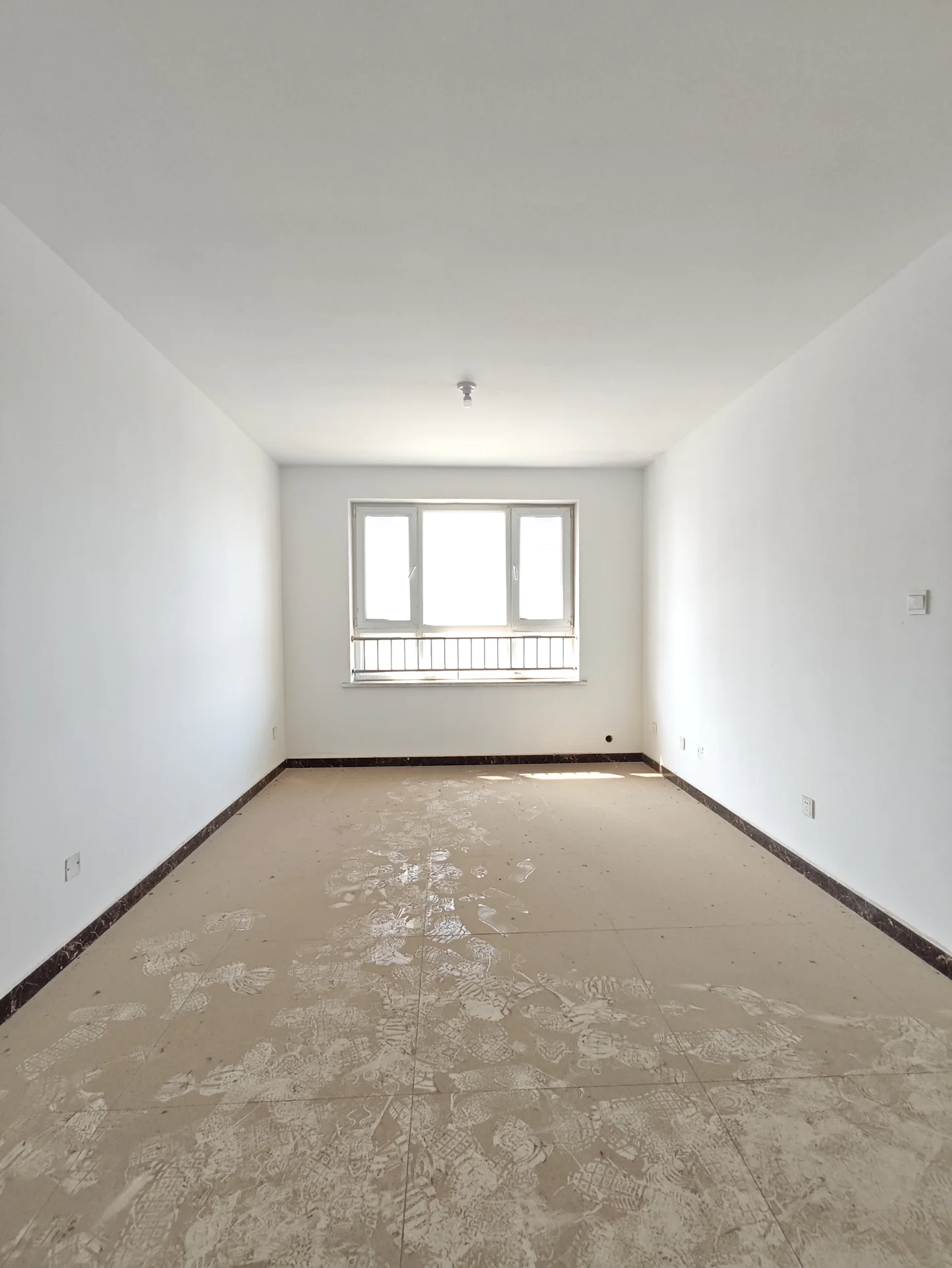 宽敞明亮的房间，白墙白地板，一扇窗户引入自然光。空间显得正在装修或翻新，没有家具或装饰。整体氛围干净整洁，给人以开阔舒适的感觉。关键字:宽敞 明亮 白墙 白地板 自然光 装修 翻新 干净整洁