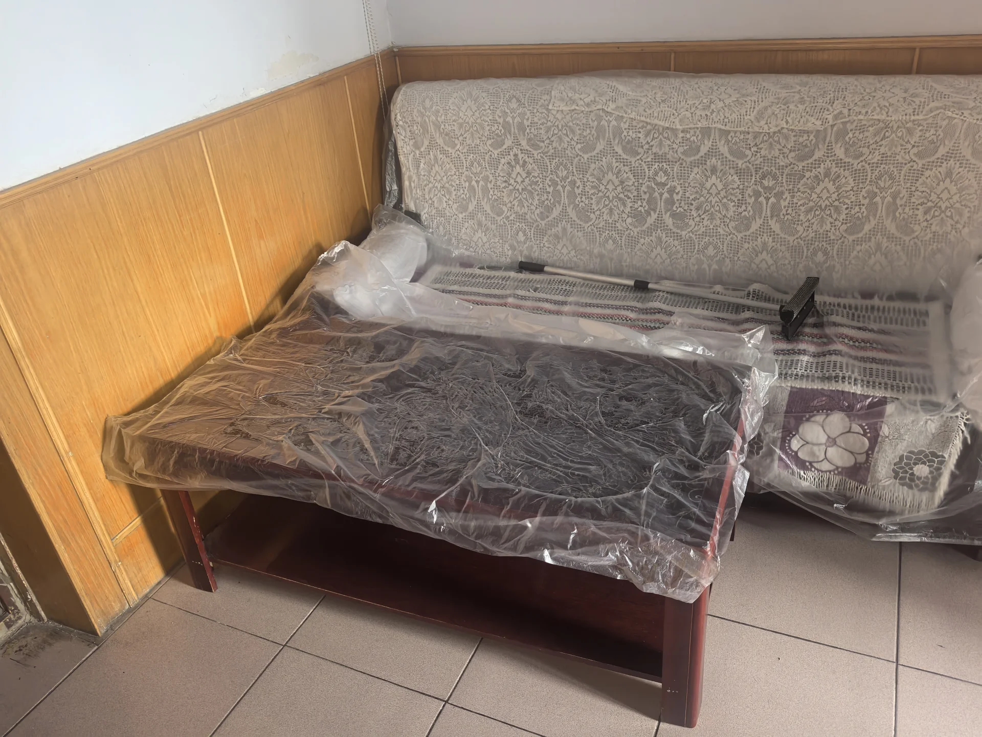 卧室木质墙面，新床被塑料覆盖，增添温馨感。两个枕头点缀床上，房间整洁有序，营造宁静氛围。关键字:卧室 木质墙面 新床 塑料覆盖 枕头 整洁有序 宁静氛围