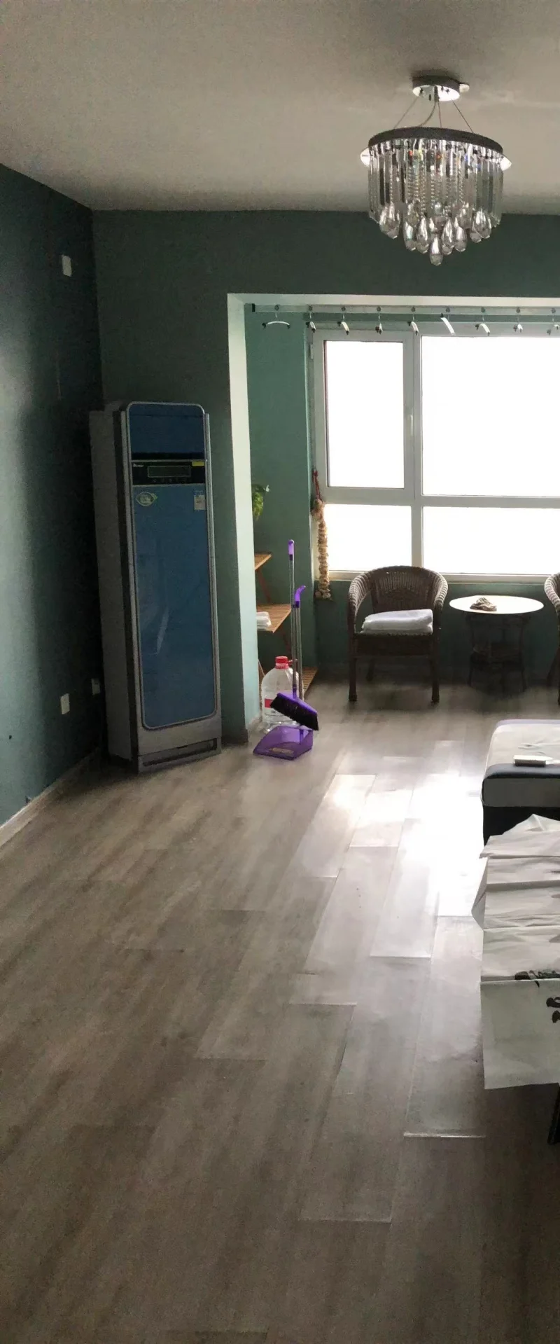 宽敞明亮的客厅，木质地板和沙发营造温馨氛围，吊灯增添优雅设计，书籍散落表明是放松或阅读的好地方。关键字:客厅 大窗户 自然光 木质地板 沙发 吊灯 书籍