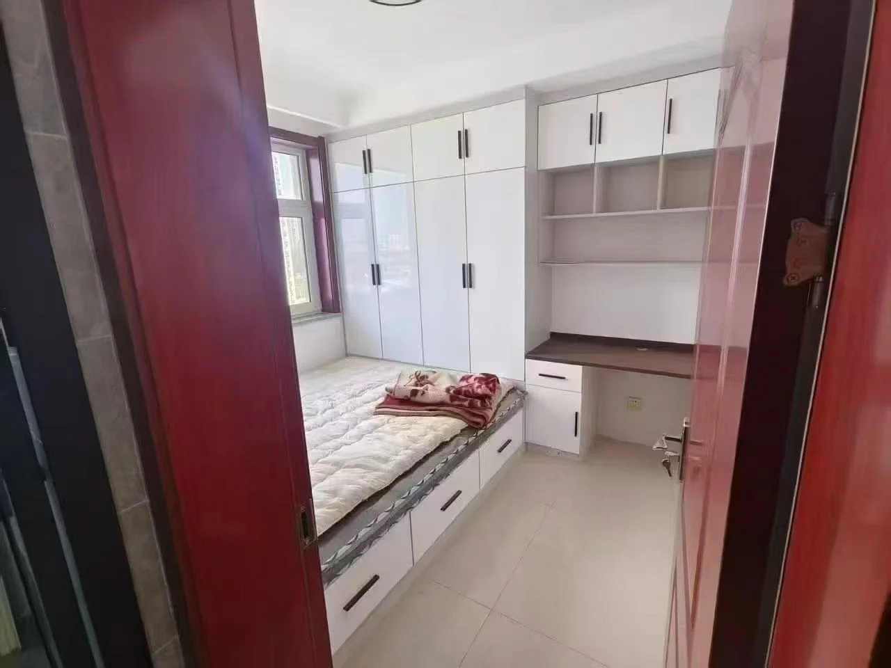 小卧室，白墙白柜，整洁干净。床铺整齐，两扇窗户引入自然光，营造宁静氛围。简约风格，以白色为主色调。关键字:小卧室 白墙 白柜 整洁 床铺整齐 自然光 宁静氛围 简约风格