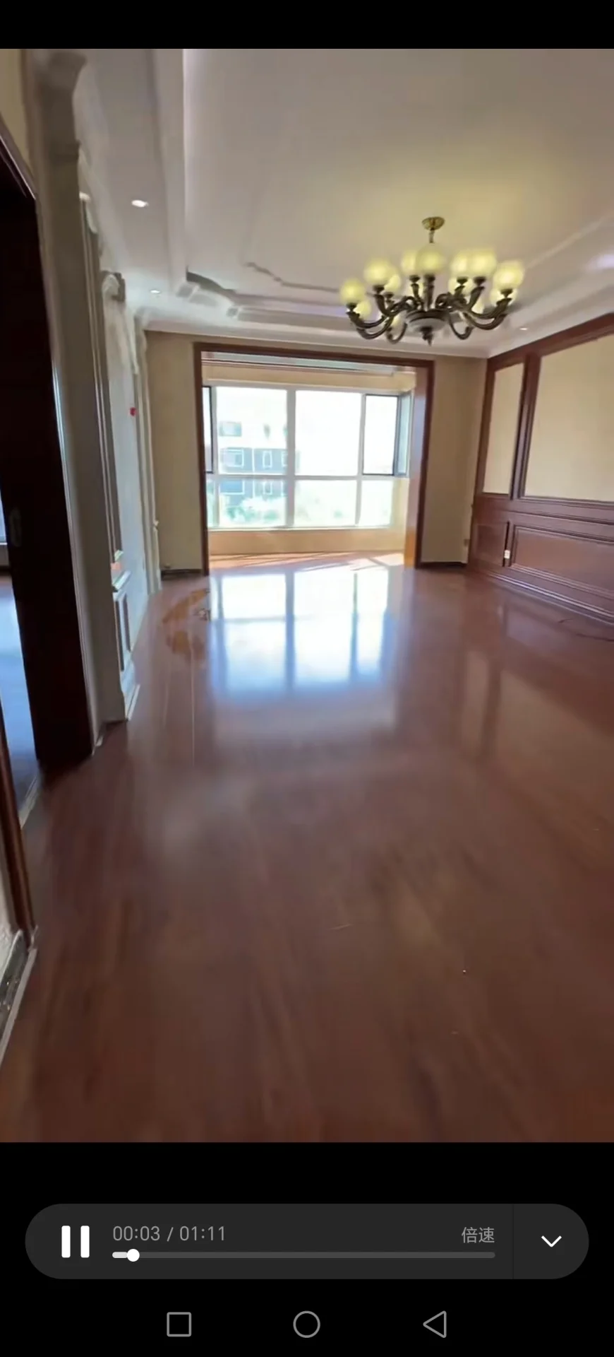 宽敞明亮的房间，木质地板，两侧各有窗户，吊灯增添优雅氛围，角落放置手机。关键字:宽敞 明亮 木质地板 窗户 吊灯 手机