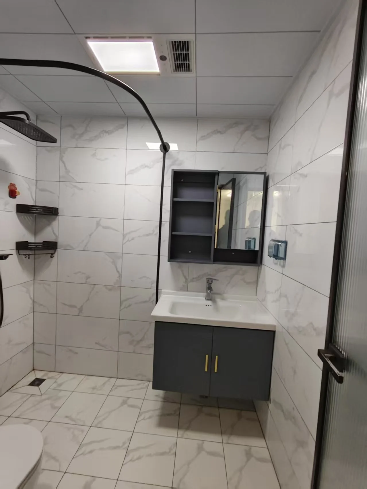 小而整洁的卫生间，白色瓷砖地面，大理石台面，带有淋浴间。两个洗手盆，其中一个在悬挂灯下。整体氛围干净整洁，瓷砖墙面和地板营造出简约感。关键字:小卫生间 白色瓷砖 大理石台面 淋浴间 两个洗手盆 悬挂灯