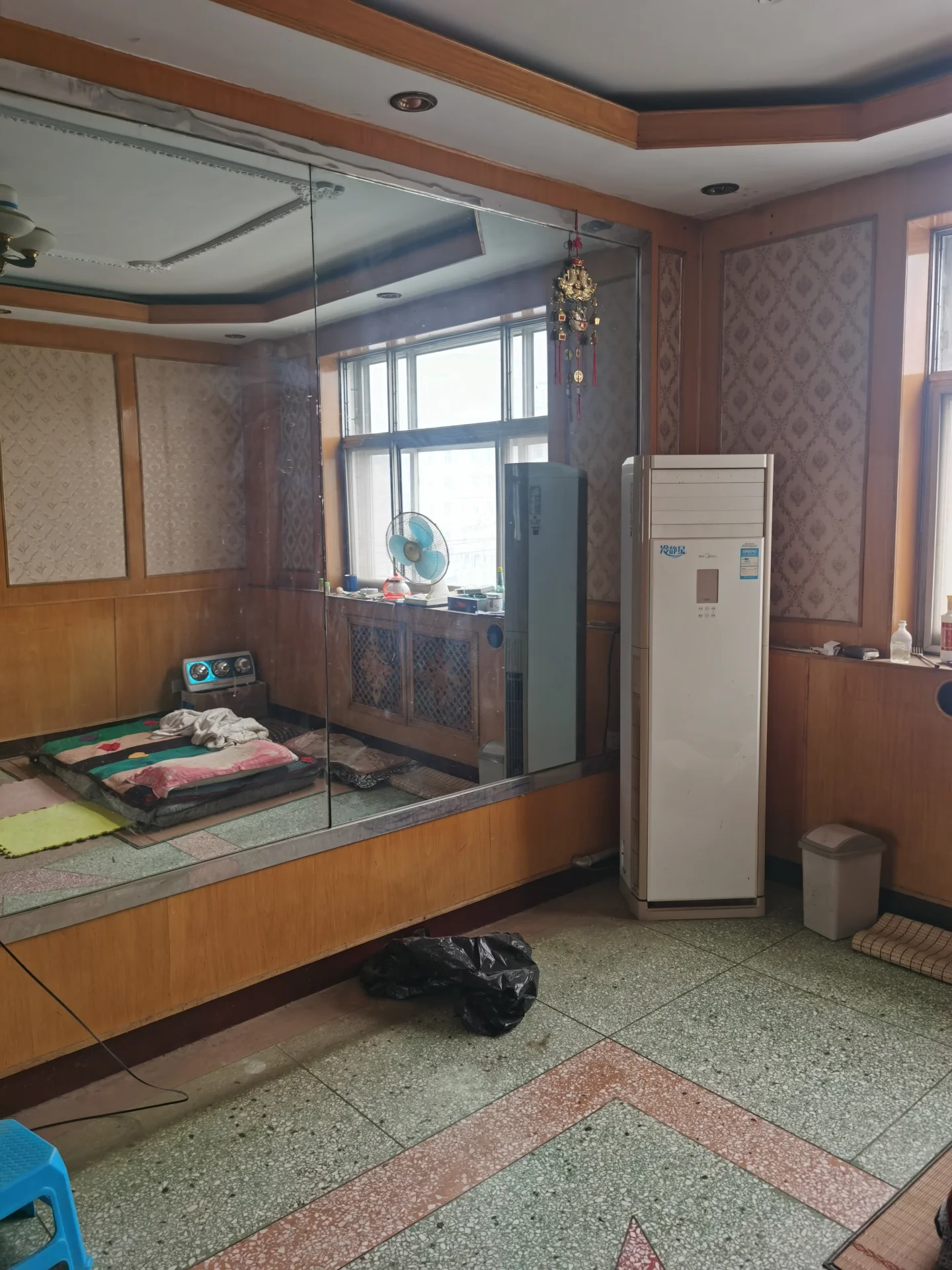 小而整洁的客厅，木地板和瓷砖墙，冰箱角落放置，微波炉在其上，两侧各有沙发，墙上挂有电视。氛围宁静宜人，无杂乱。现代舒适的室内设计，疑似公寓。关键字:小客厅 木地板 瓷砖墙 冰箱 微波炉 沙发 电视 宁静氛围 现代设计 公寓