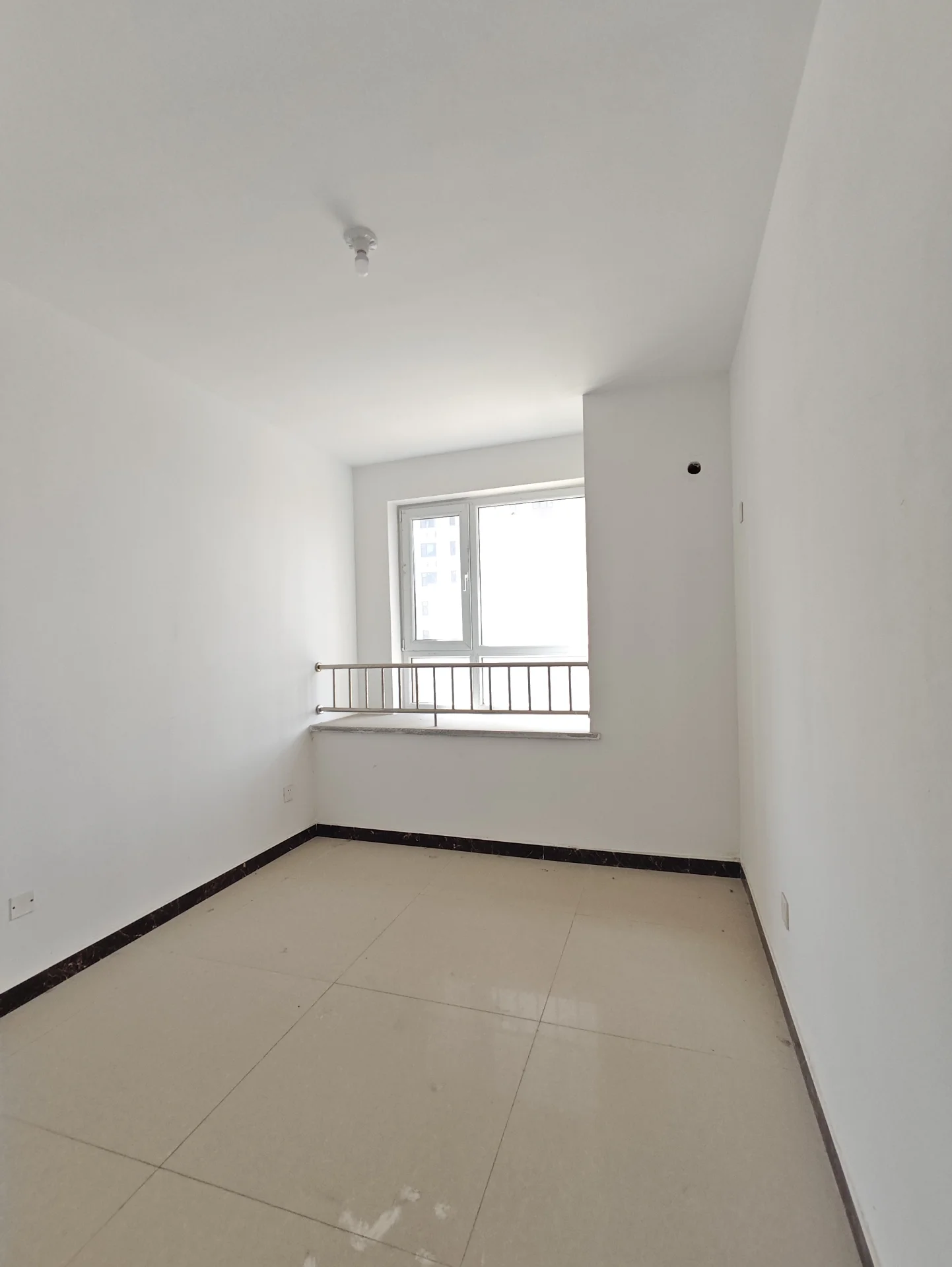 小房间，白墙白地板，一扇窗户引入自然光，空无一物，显得冷清。窗外有露台，整体氛围宁静。关键字:小房间 白墙 自然光 空无一物 露台 宁静