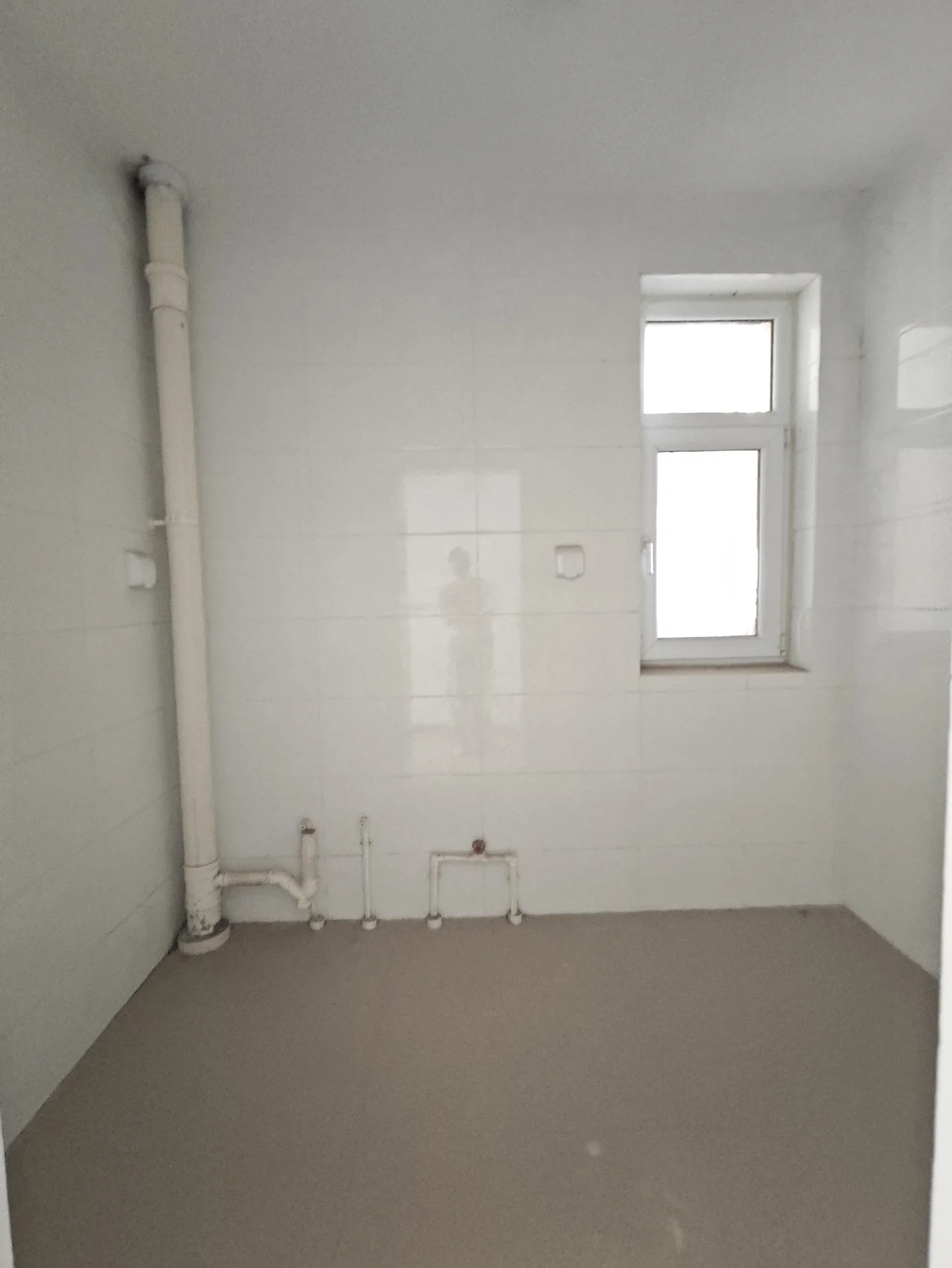 小而简洁的白色浴室，窗户透光，空无一人，显得冷清。整体风格简约实用，没有奢华装饰。关键字:小 bathroom 白色 窗户 空无一人 简约实用