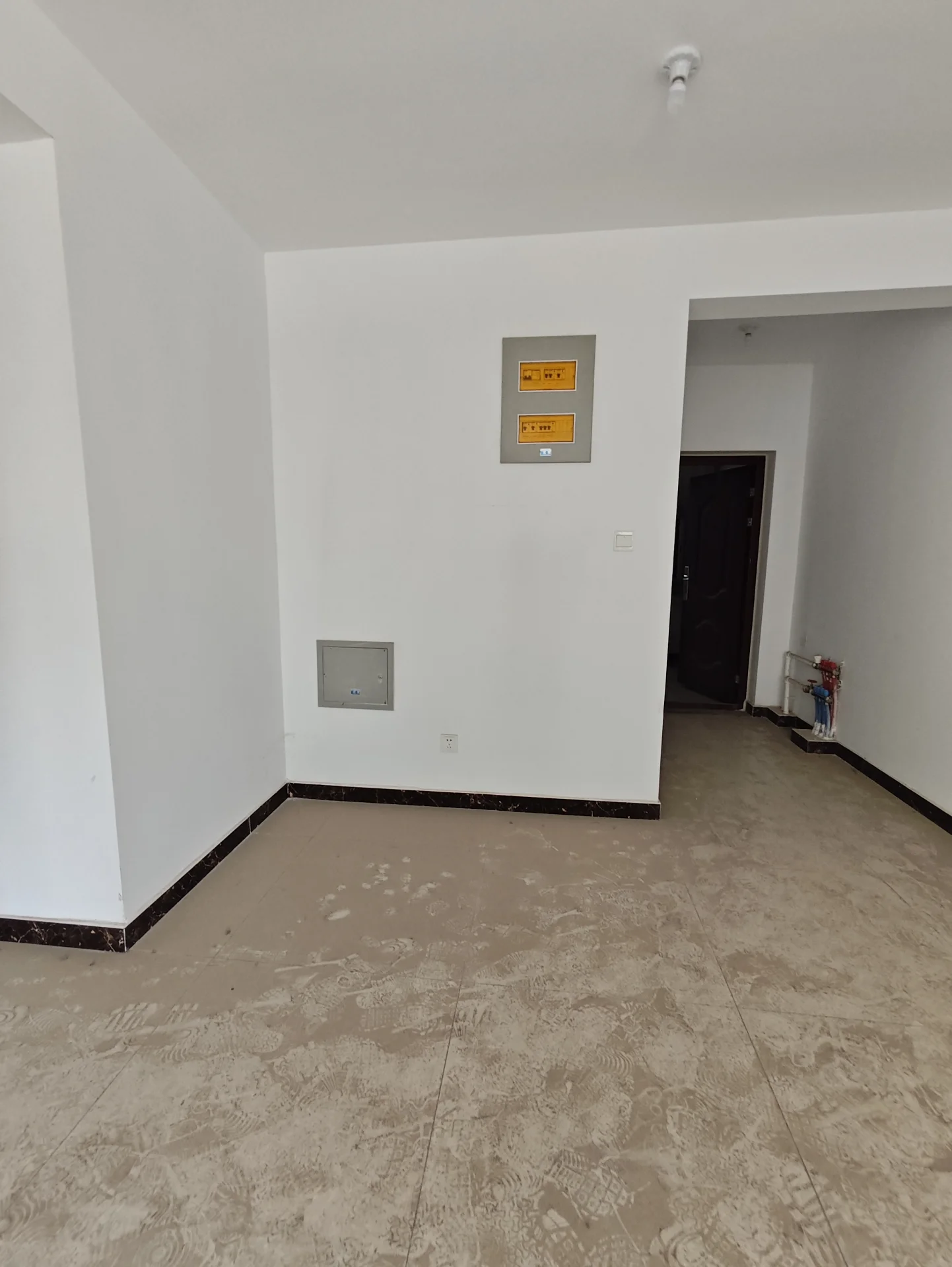 宽敞明亮的房间，白墙白地板，简约现代风格，门上挂有三个指示牌，宁静的氛围，仿佛是新装修或待入住的空间。关键字:宽敞 明亮 白墙 白地板 简约现代 指示牌 宁静 新装修 待入住