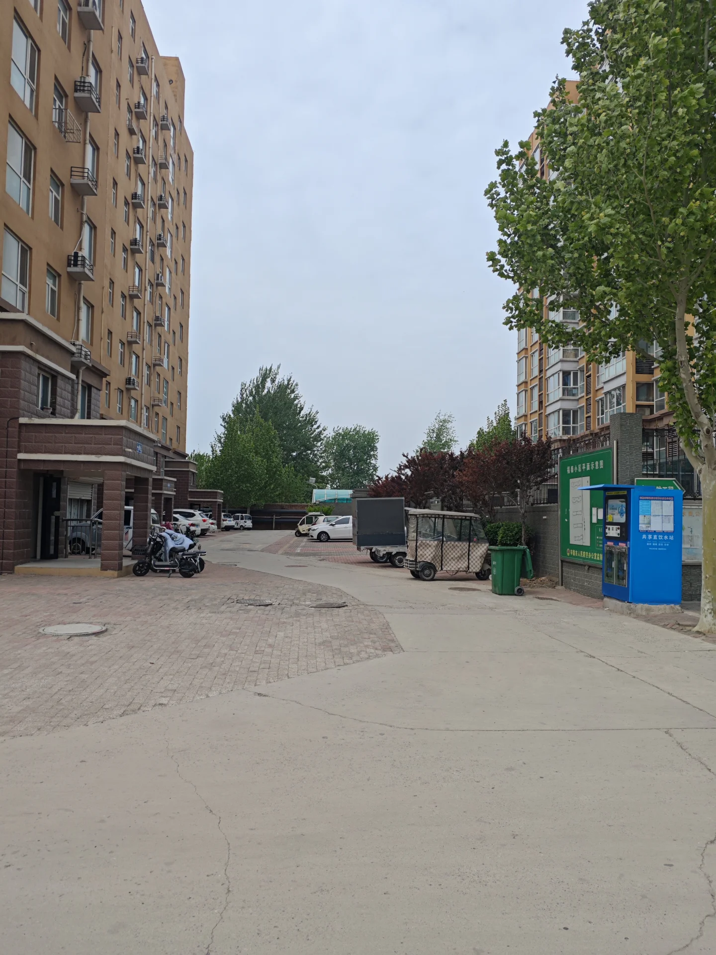 安静的街道，两侧有几栋老式建筑，砖墙外观。街道两旁有树木，提供绿意。 sidewalks上停着几辆车和摩托车，显示此时不忙。氛围宁静祥和，无人可见。整体呈现一个充满绿意和建筑魅力的宁静城市环境。关键字:安静 城市街道 老式建筑 砖墙 树木 绿意 宁静祥和