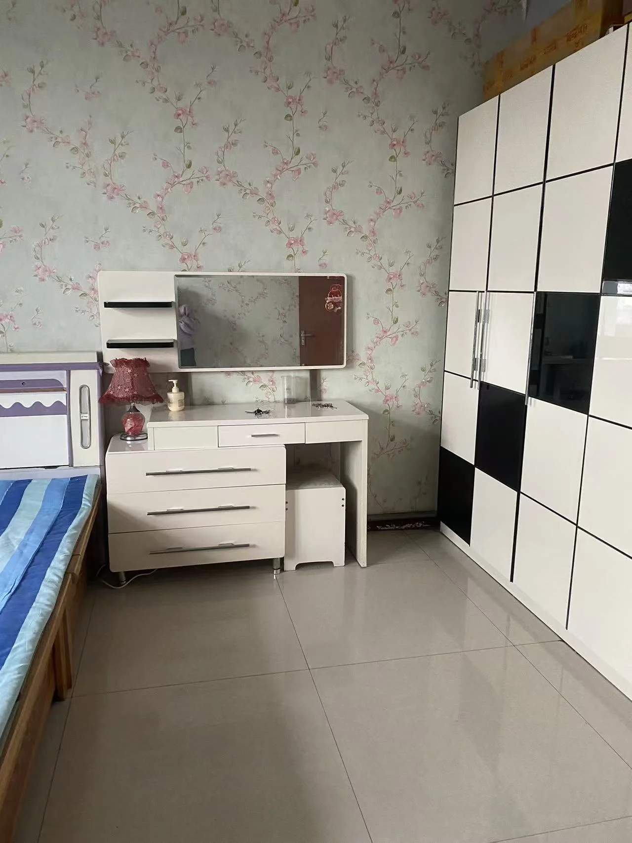 小卧室，黑白家具搭配，白色衣柜、书桌、床头柜，黑色壁橱，墙上镜框映衬书桌，格子墙面增添独特风格，氛围宁静整洁。关键字:小卧室 黑白家具 白色衣柜 书桌 床头柜 黑色壁橱 镜框 格子墙面