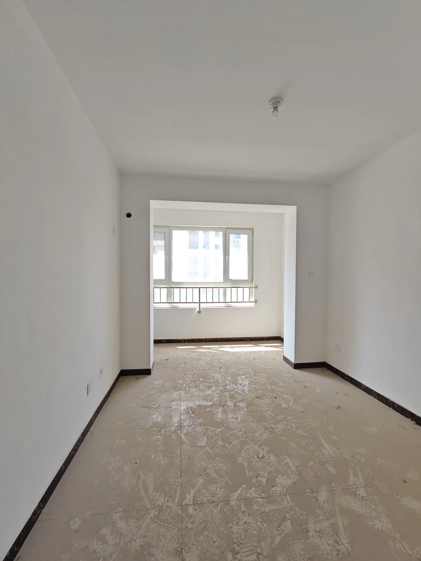 白墙白顶的房间，正在装修中，自然光透过窗户洒入，宽敞的空间营造出清新的氛围。简洁的布局和安静的环境，没有人在场。关键字:白墙 天花板 装修中 自然光 宽敞空间 清新的氛围 简洁布局 安静环境