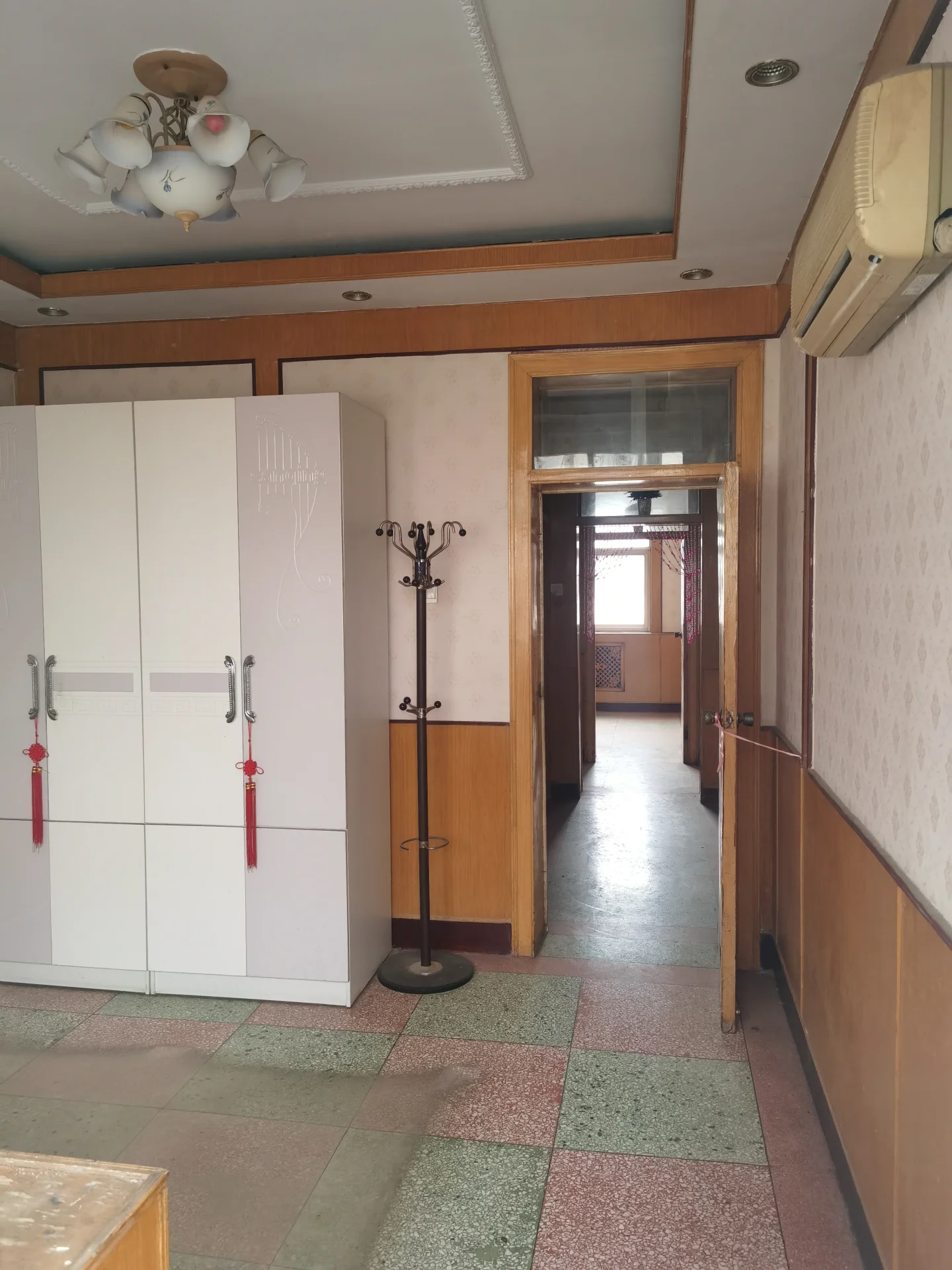 狭窄老旧走廊，白墙瓷砖地，吊灯点缀，空旷幽静，古风浓厚，营造出宁静祥和的氛围。关键字:小走廊 老旧房屋 白墙 瓷砖地 吊灯 空旷 幽静 古风