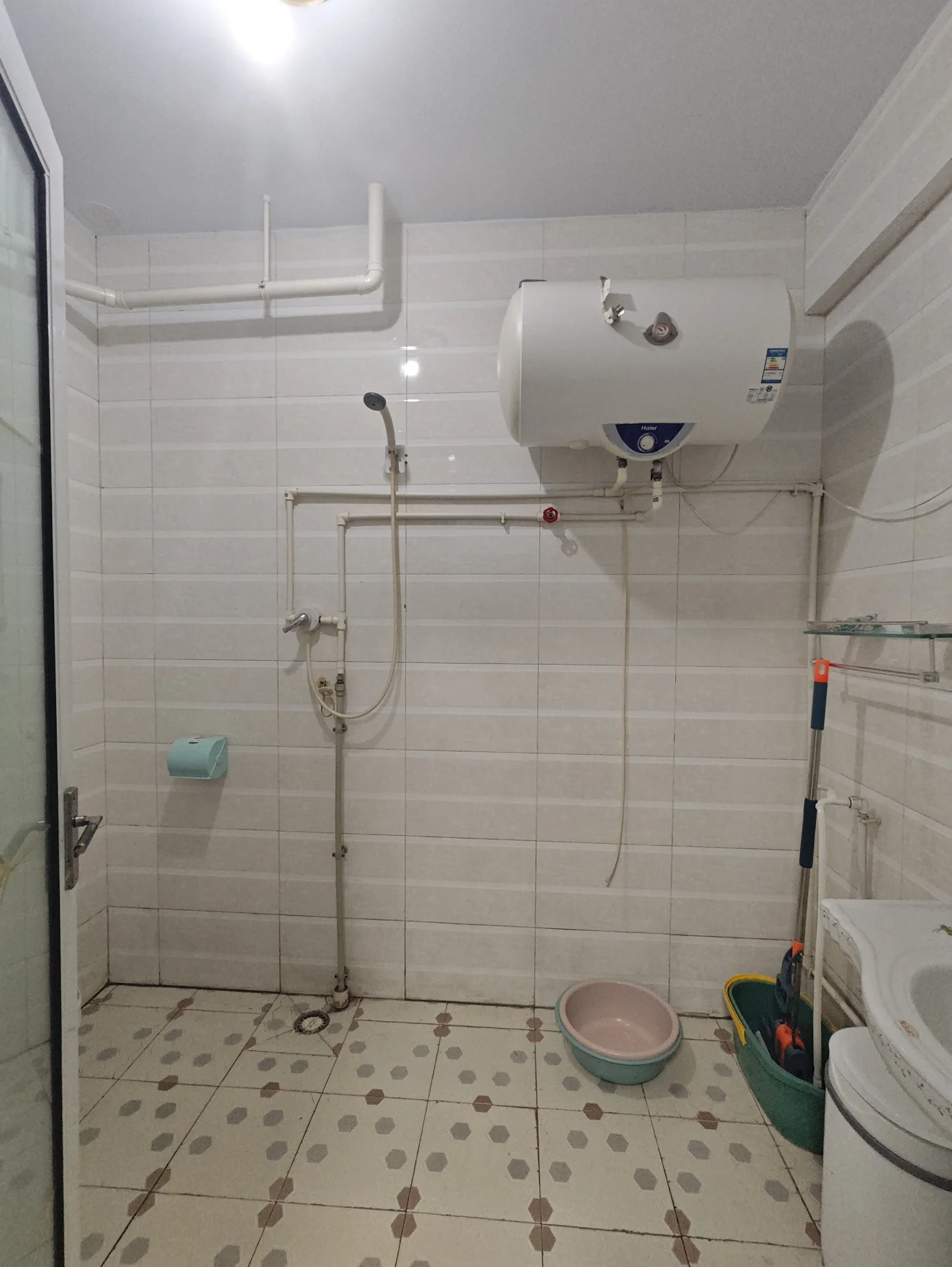 小白色浴室，瓷砖墙面和地面，左侧有马桶，右角有洗手台，地上两盆花一在中央，一靠右侧墙。目前空无一人，氛围宁静。关键字:小浴室 白色 瓷砖 马桶 洗手台 盆花