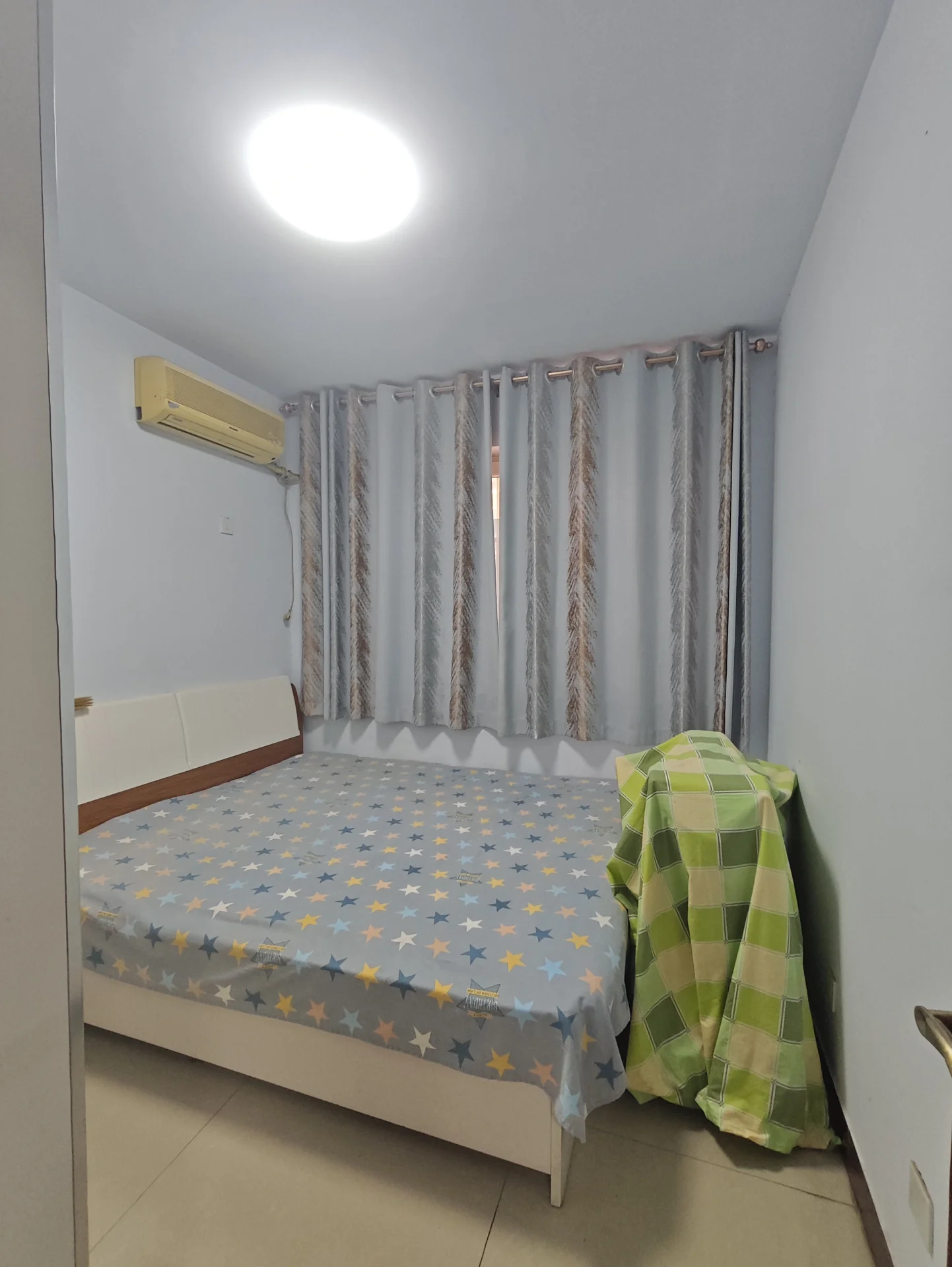 小卧室，白墙白床，大吊灯提供充足光线，窗帘开启时自然光充足，宁静舒适的氛围。关键字:小卧室 白墙 白床 大吊灯 窗帘 自然光 宁静舒适