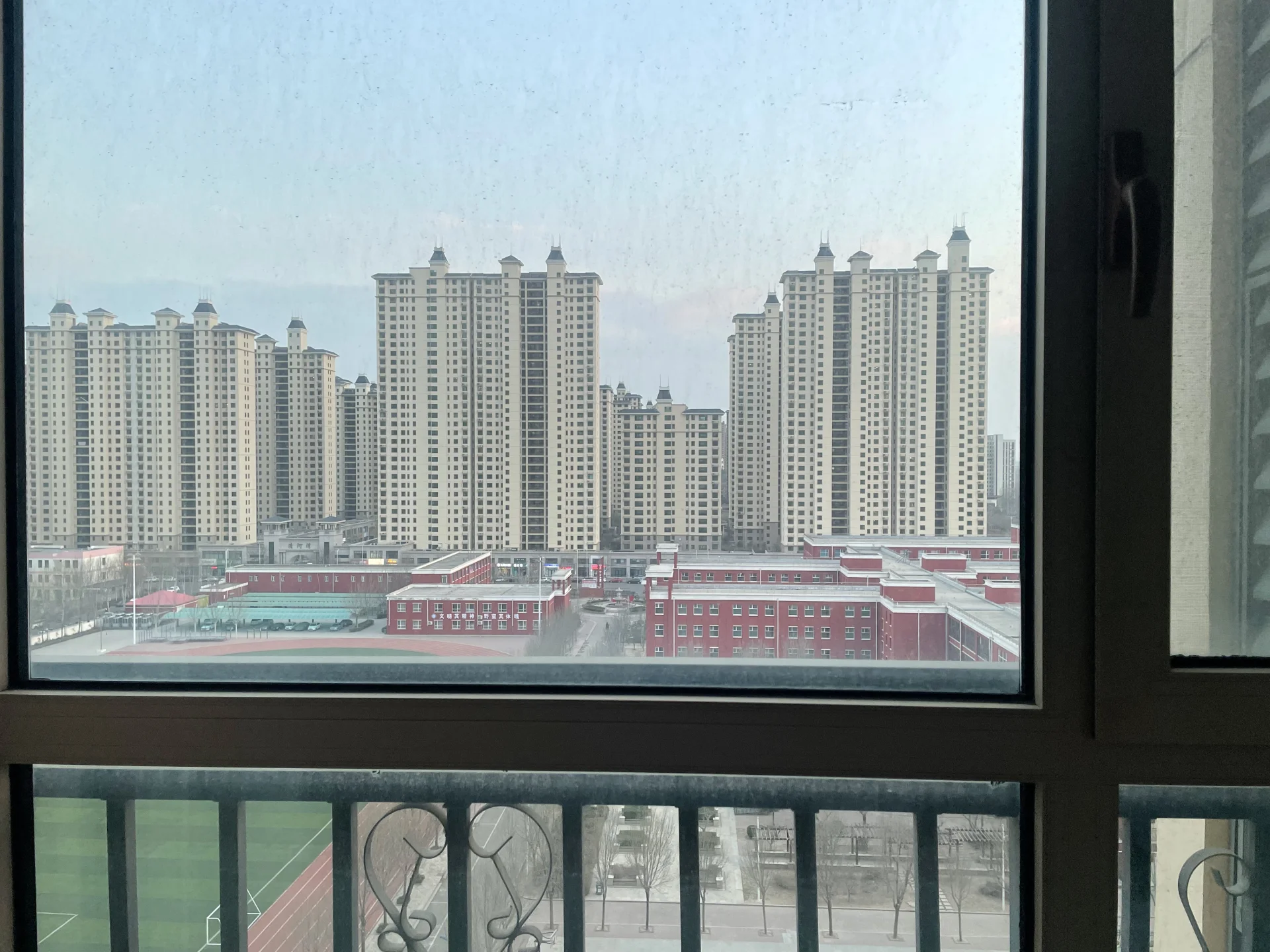 多栋高层白色住宅楼的外部立面，背景是城市景观和低层建筑群，整体呈现典型的城市社区建筑外观，氛围宁静和谐。