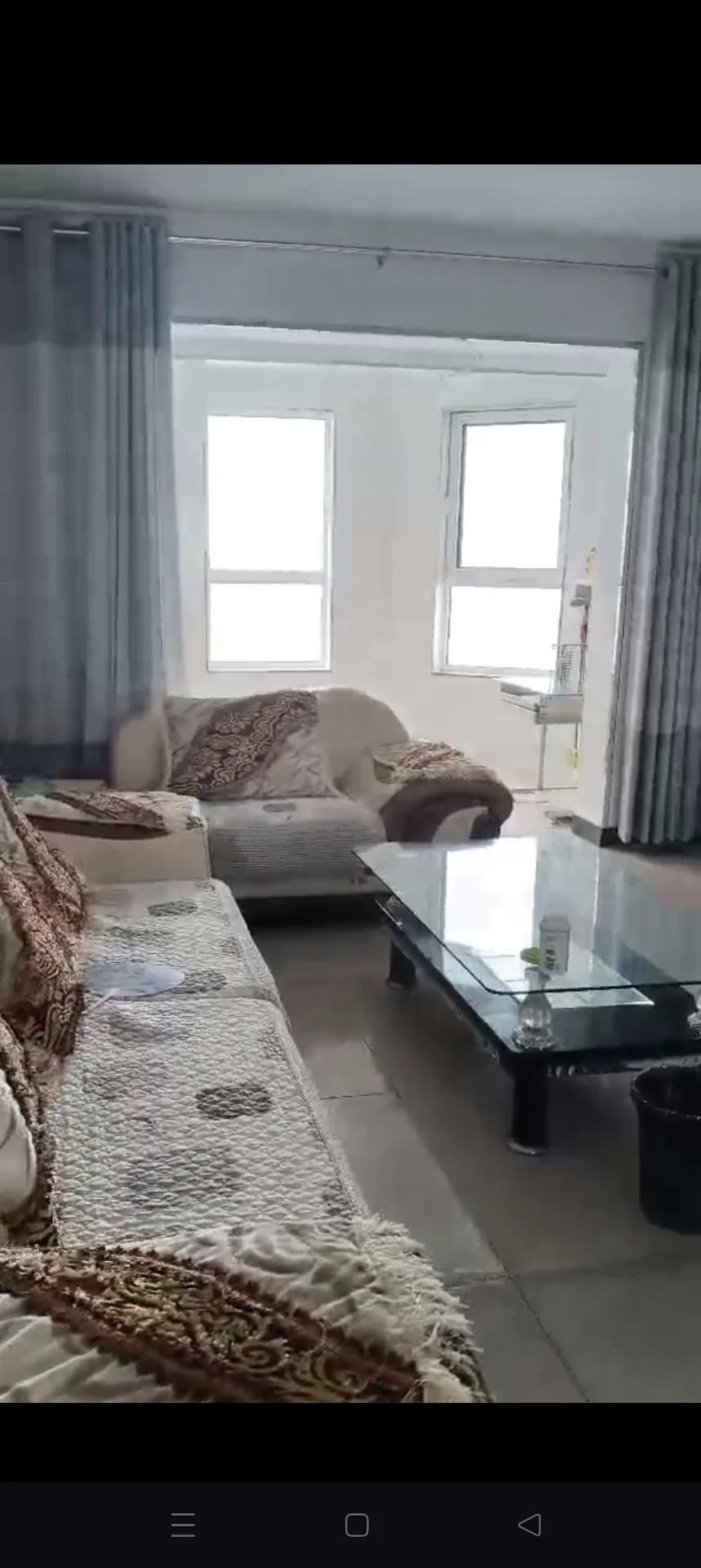 客厅场景，沙发和窗帘是主要元素。采光良好，整体呈现温馨舒适的居家氛围。