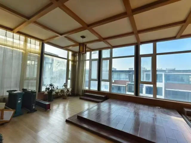 一个具有木质框架结构和多扇大窗户的室内空间，地面铺设了木质地板和深色瓷砖，采光良好，整体呈现出一种结构感强、光线充足的居住环境。