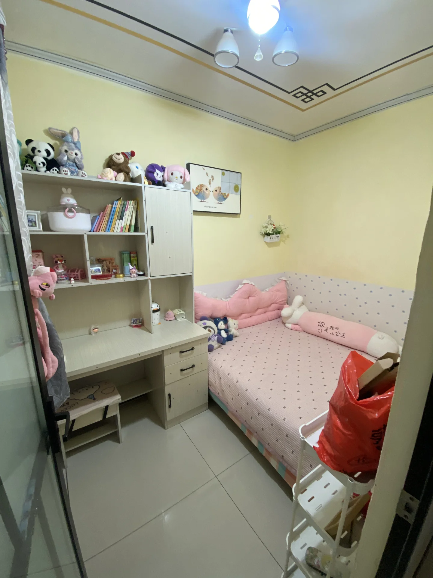卧室场景，墙面采用浅黄色调，配有床铺、多层书架和衣柜。采光良好，整体呈现温馨、温馨的居住氛围。