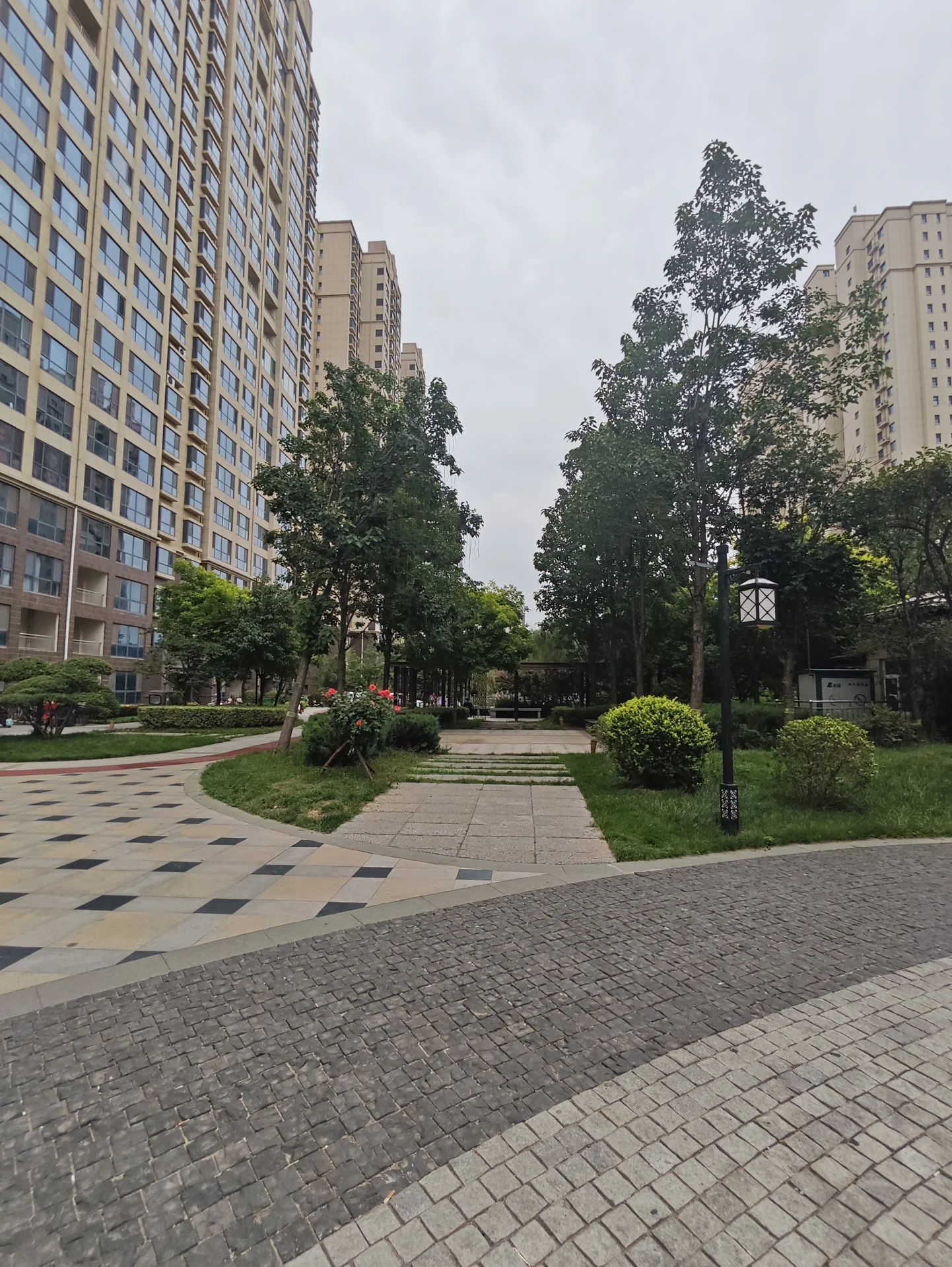 高层住宅的外部立面清晰可见，建筑主体呈浅色调，周围环绕着茂密的树木和精心维护的绿化带，整体呈现出一种宁静、宜居的社区氛围。