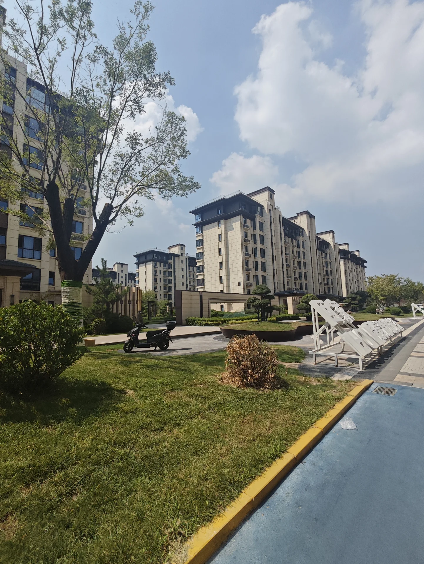 多栋现代风格的白色高层住宅楼群，建筑立面整洁，周围有修剪整齐的草坪和绿植环绕，整体呈现出宁静、宜居的社区建筑外观。