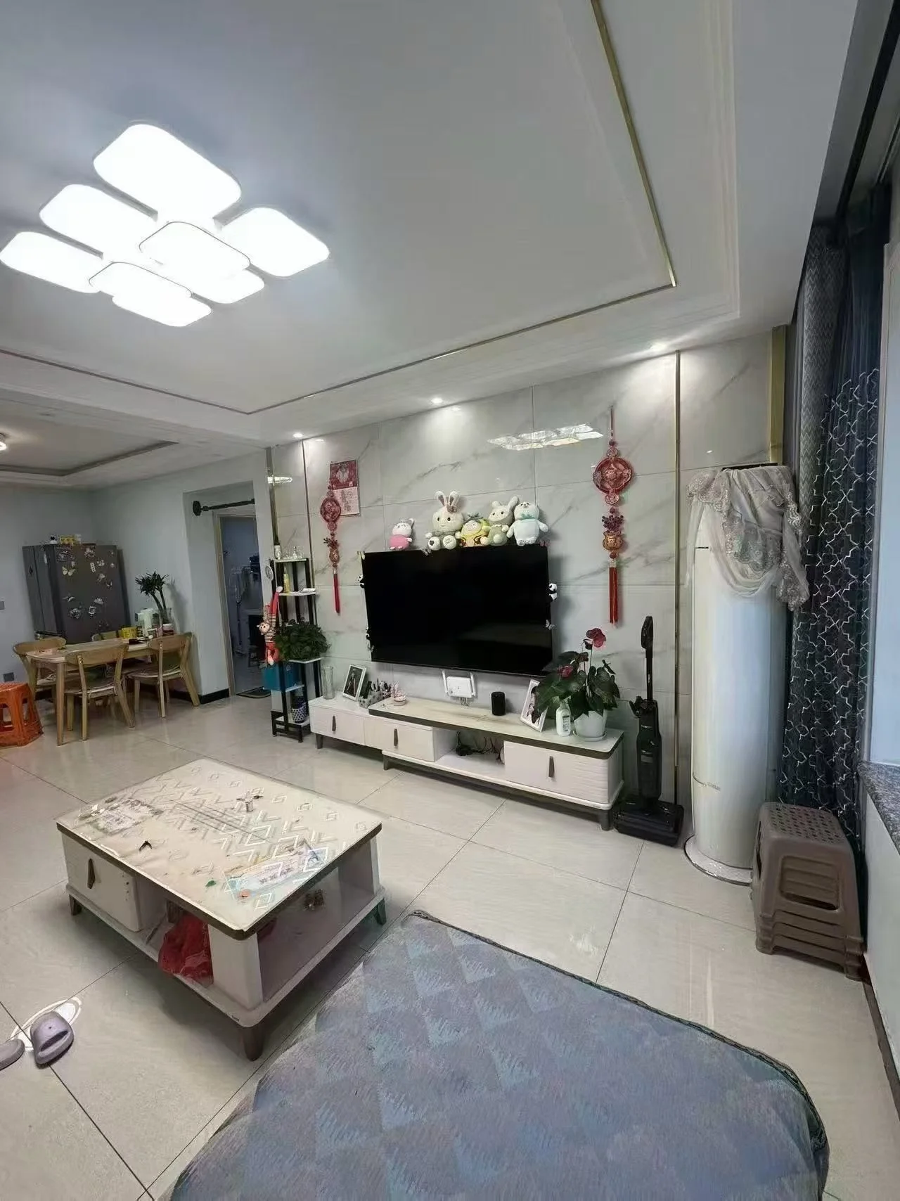 客厅场景，墙面采用浅色调，配有大型平板电视和电视柜。采光良好，整体呈现现代简约装修风格，氛围整洁舒适。