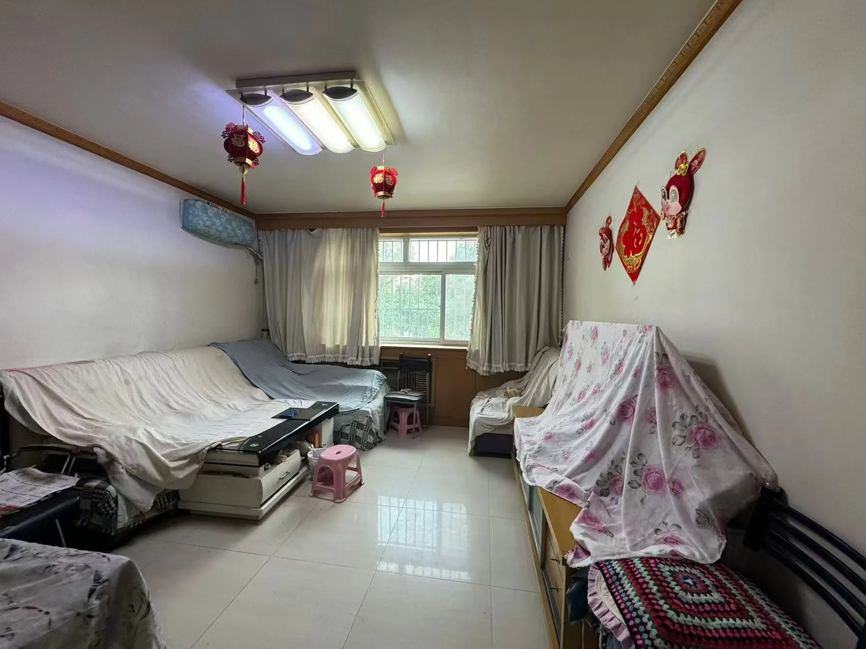 卧室场景，墙面为浅色调，配有床铺、衣柜和窗户。采光良好，整体呈现朴素、温馨的居住氛围。