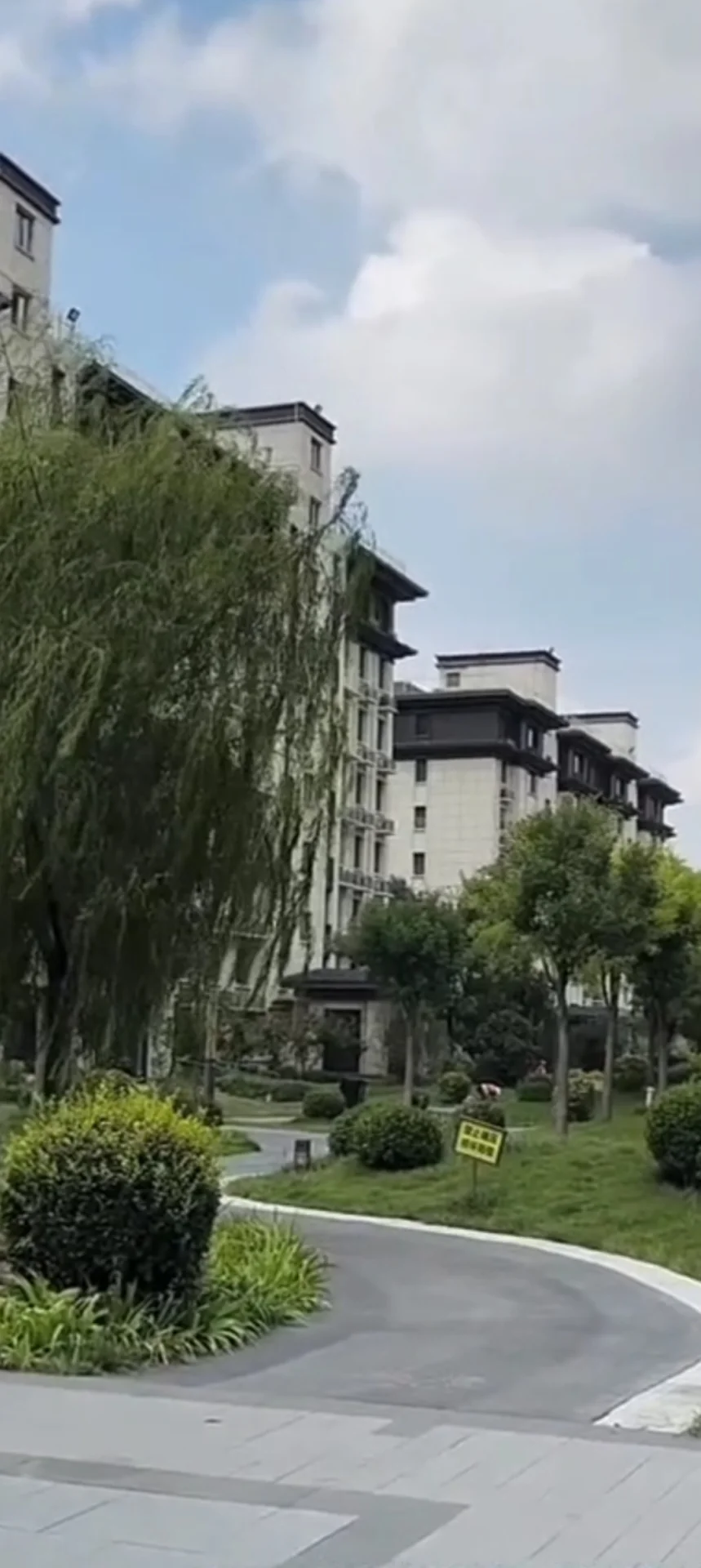 多层白色住宅建筑的外部立面，配有整齐的绿化带和草坪，整体环境宁静和谐，展现出社区住宅的居住氛围。