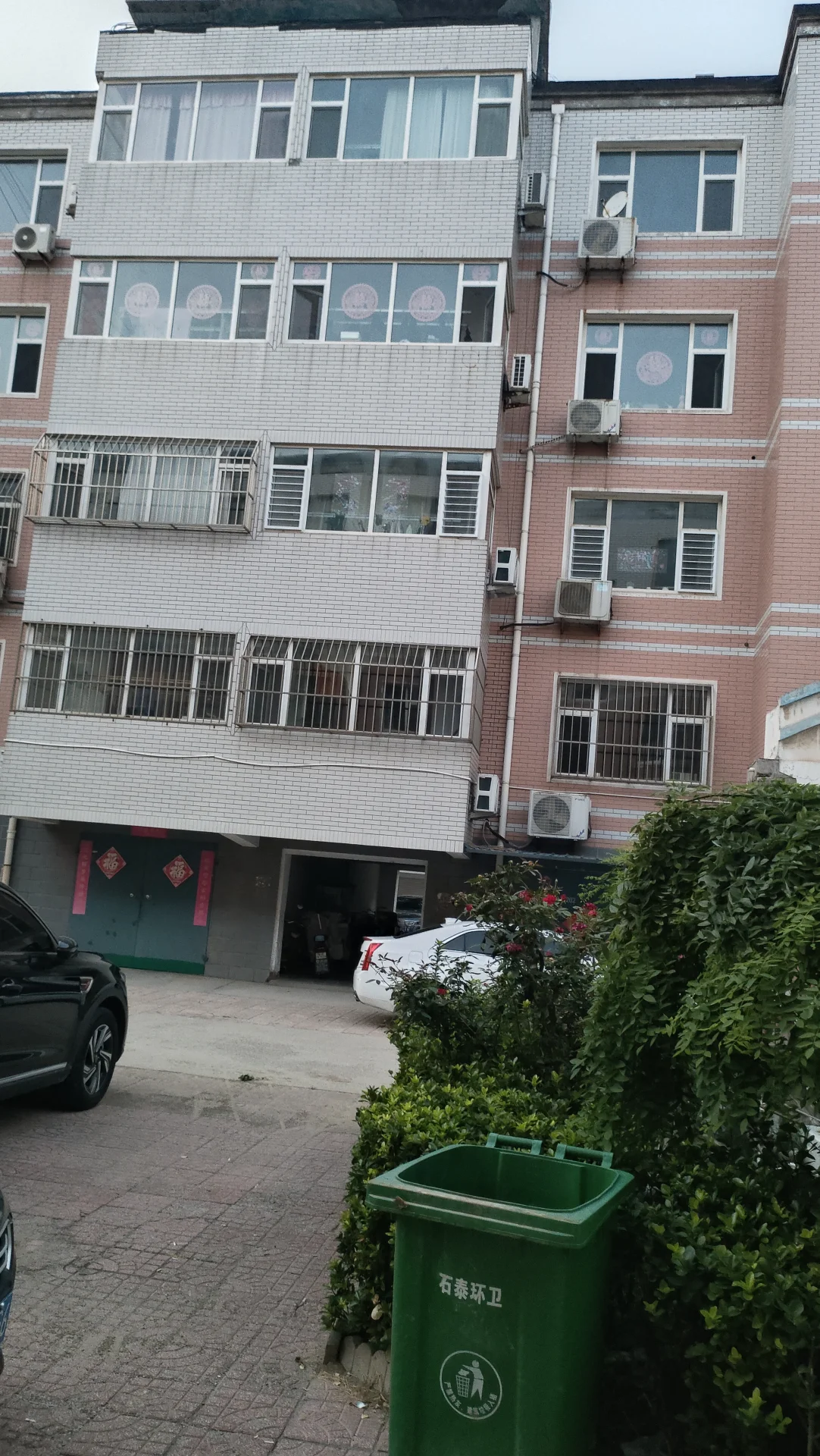 一栋多层住宅的外部立面，外墙为浅色调，设有规则排列的窗户和阳台。建筑结构清晰，展现了社区建筑的日常居住环境，整体氛围宁静和谐。
