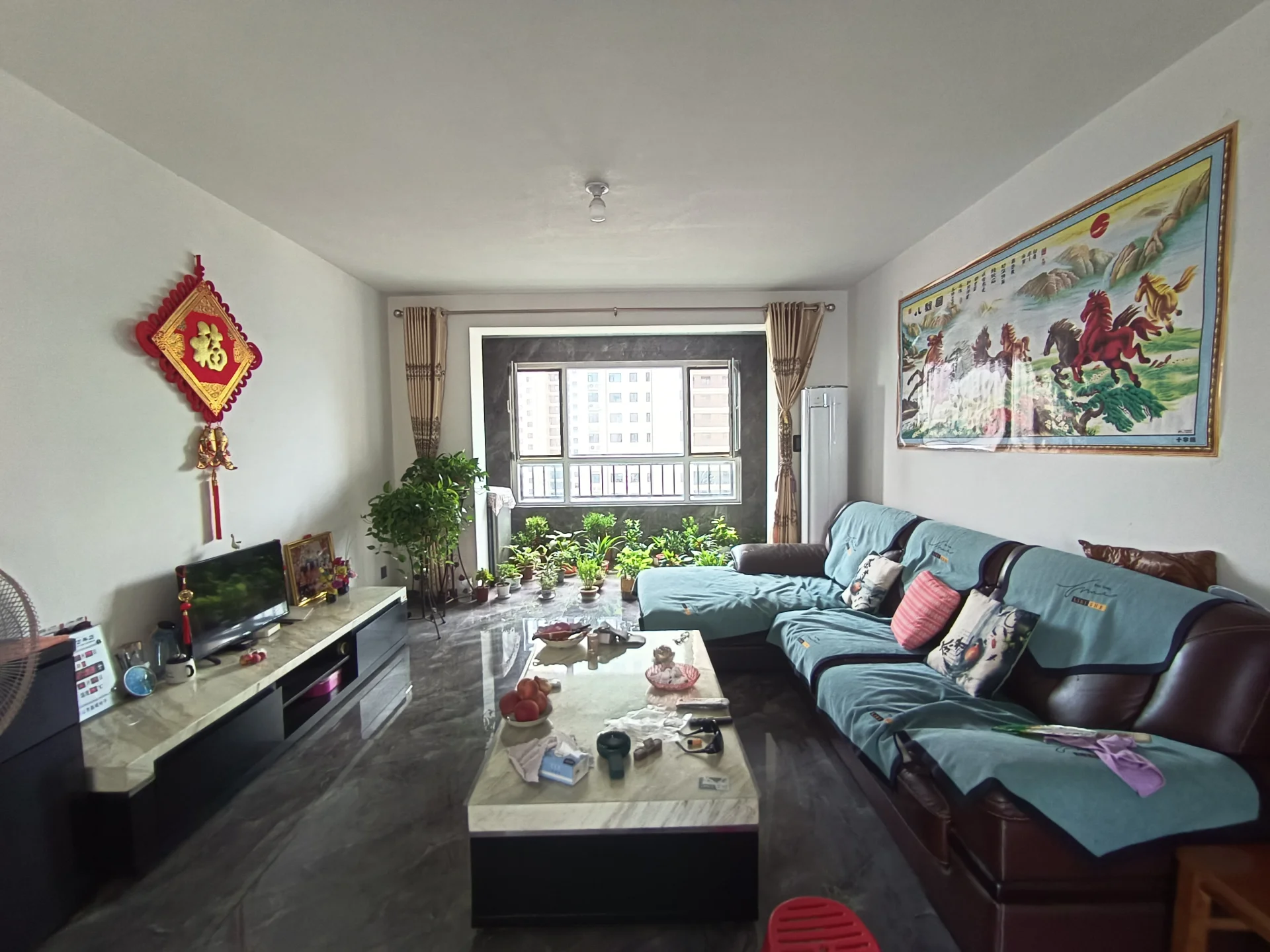 客厅场景，墙面采用浅色调，配有深色沙发和茶几。采光良好，整体呈现温馨舒适的居住氛围，装修风格偏向温馨居家风格。
