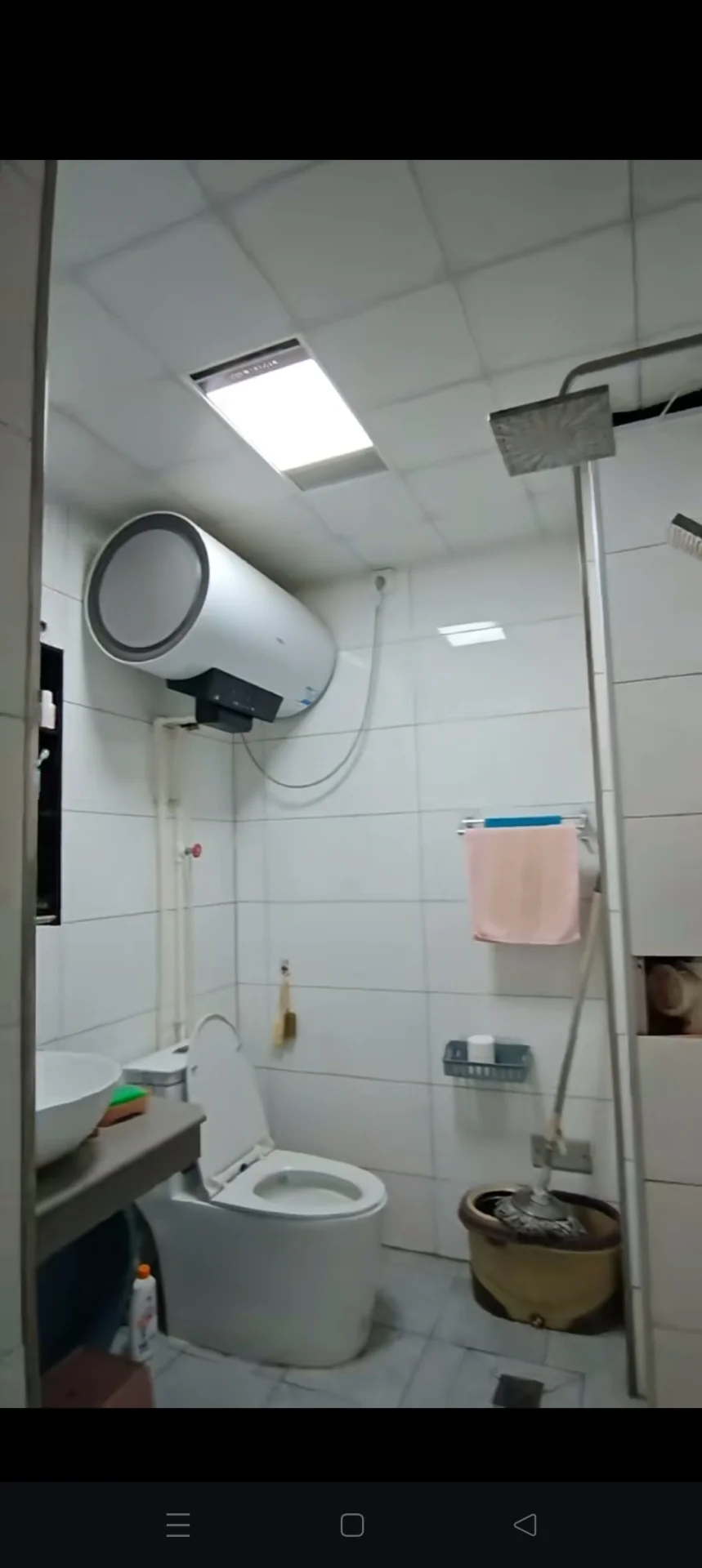 浴室空间，地面铺设米色瓷砖，功能分区明确。虽略显简陋但光线明亮，具备基础的卫浴设施。