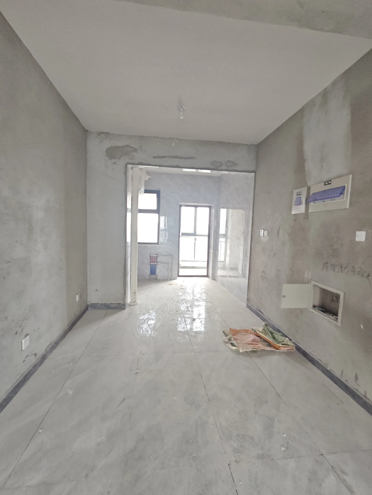 一个未装修的室内空间，以灰白色混凝土墙面和水泥地面为主，屋顶结构裸露，光线明亮，整体呈现出未完成或正在施工中的建筑内部环境。