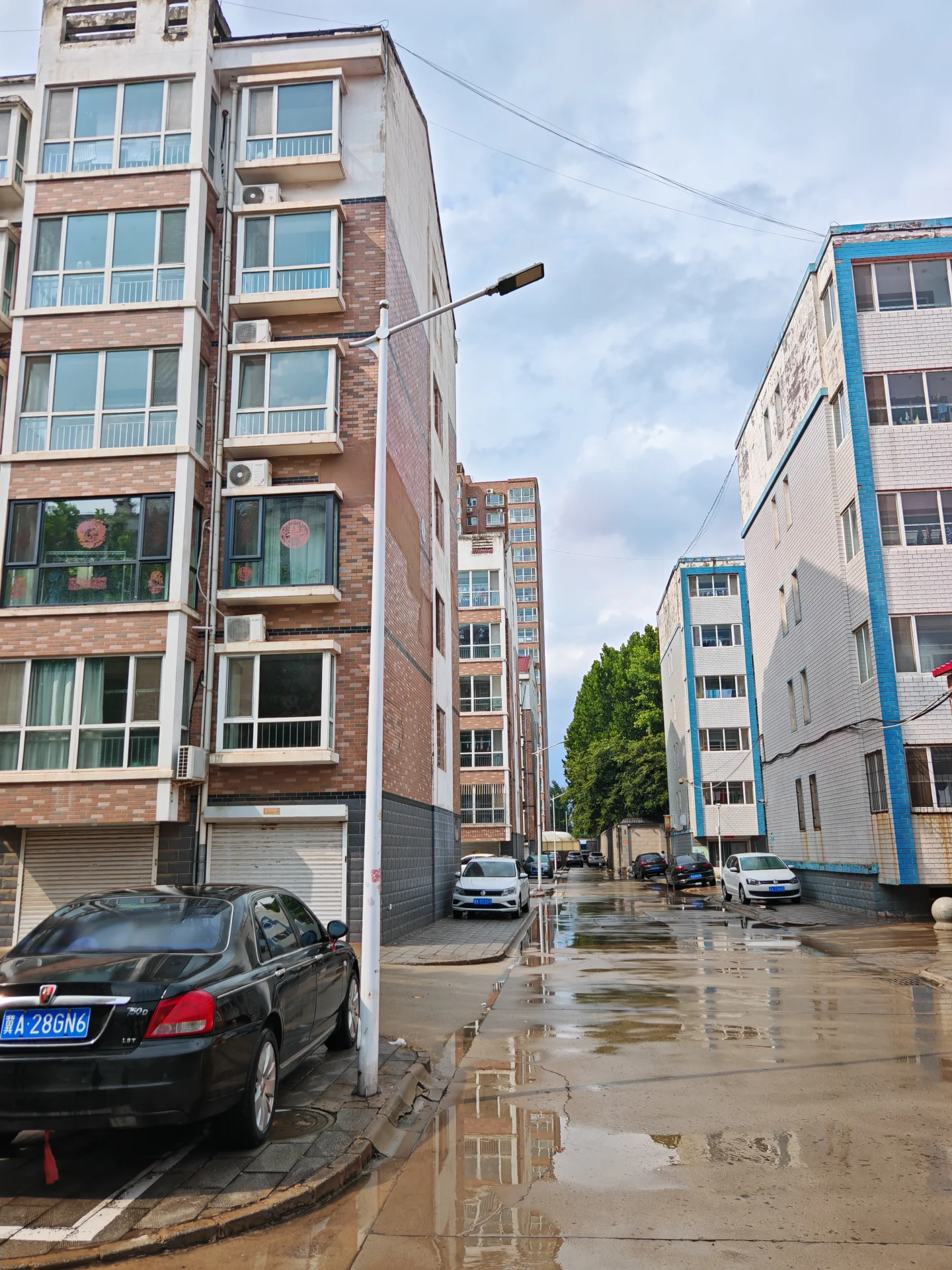 多栋多层住宅的外部立面和街道场景，建筑风格以现代简约为主，外墙材质多样，街道湿润，整体呈现出城市居住社区的建筑外观氛围。