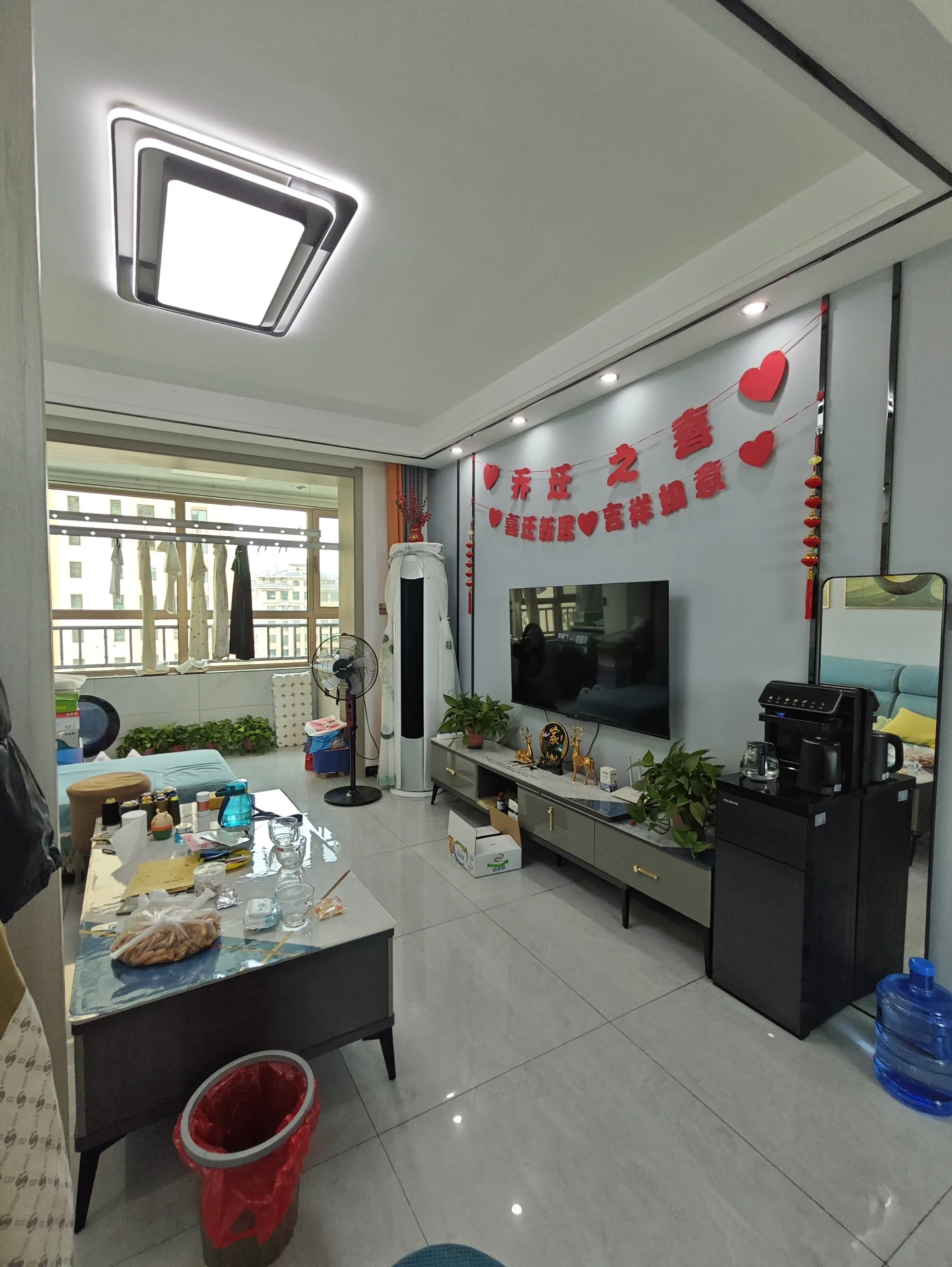 客厅场景，墙面采用浅色调，配有大型平板电视和电视柜。采光良好，整体呈现现代简约装修风格，氛围整洁舒适。
