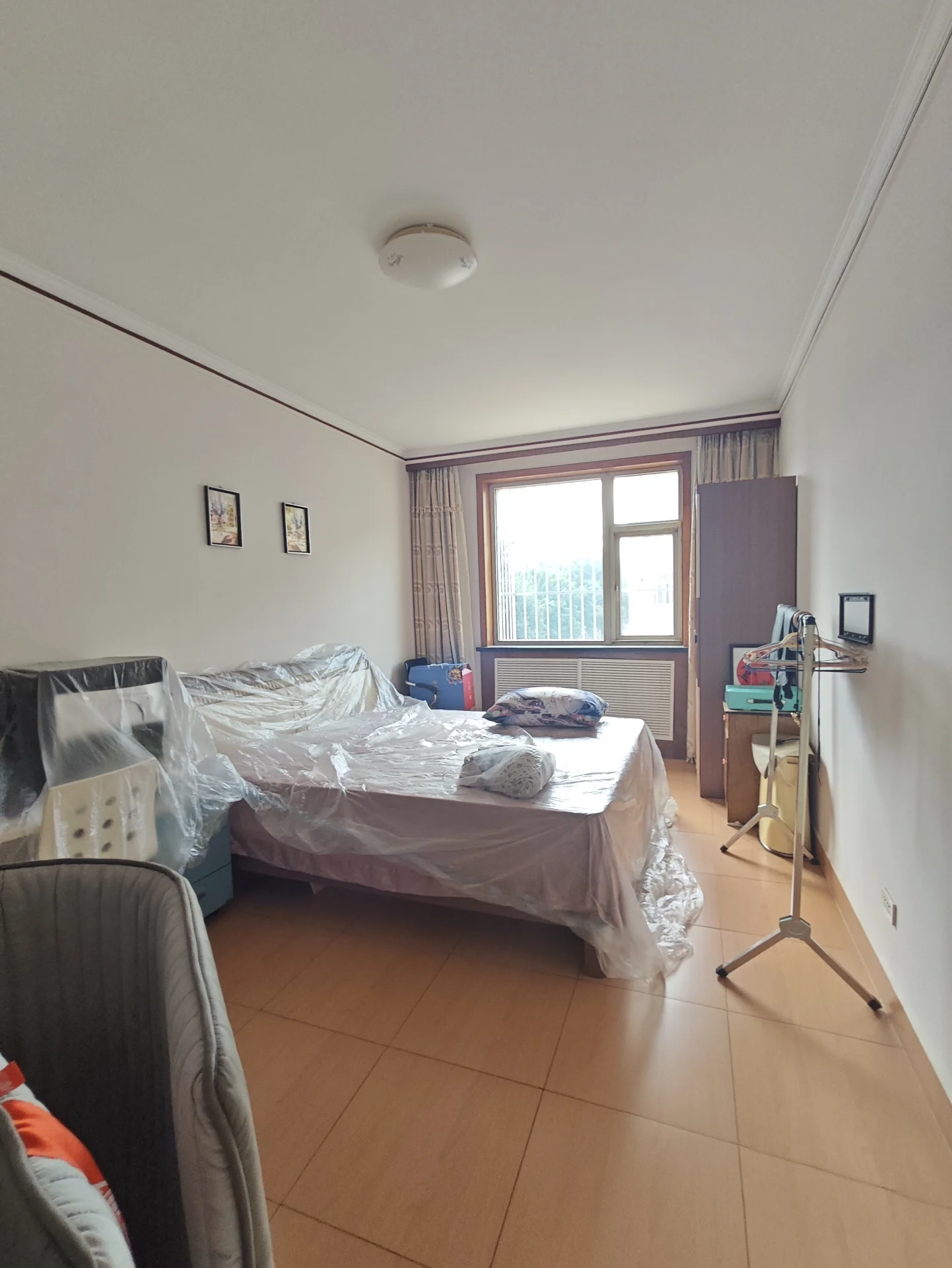 卧室场景，床铺铺设了白色床单和被褥，房间内光线充足，采光良好，整体呈现一个功能性居住环境。
