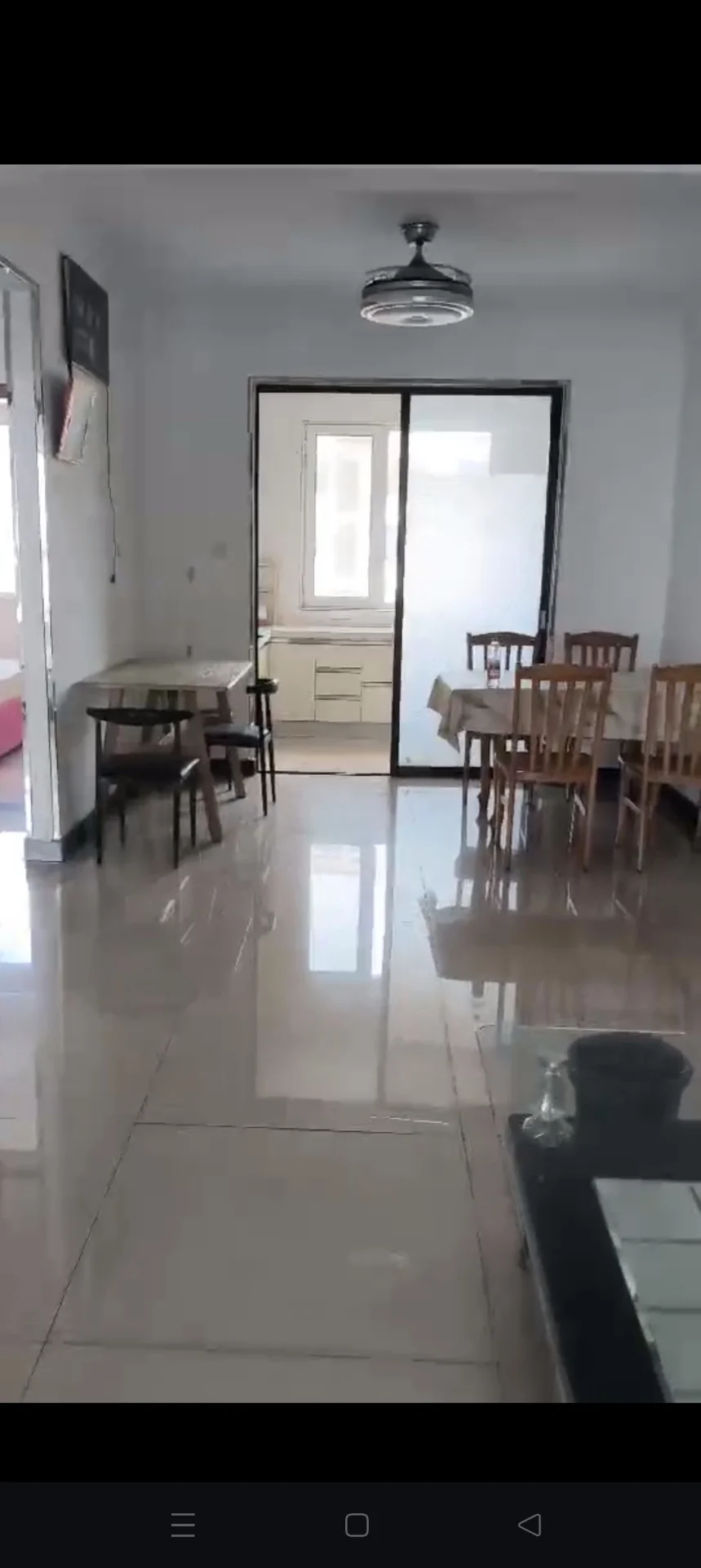 一个宽敞的室内空间，地面铺设大理石或大理石纹样，光线充足，整体呈现明亮整洁的居住环境，设有餐桌椅和窗户，氛围温馨舒适。