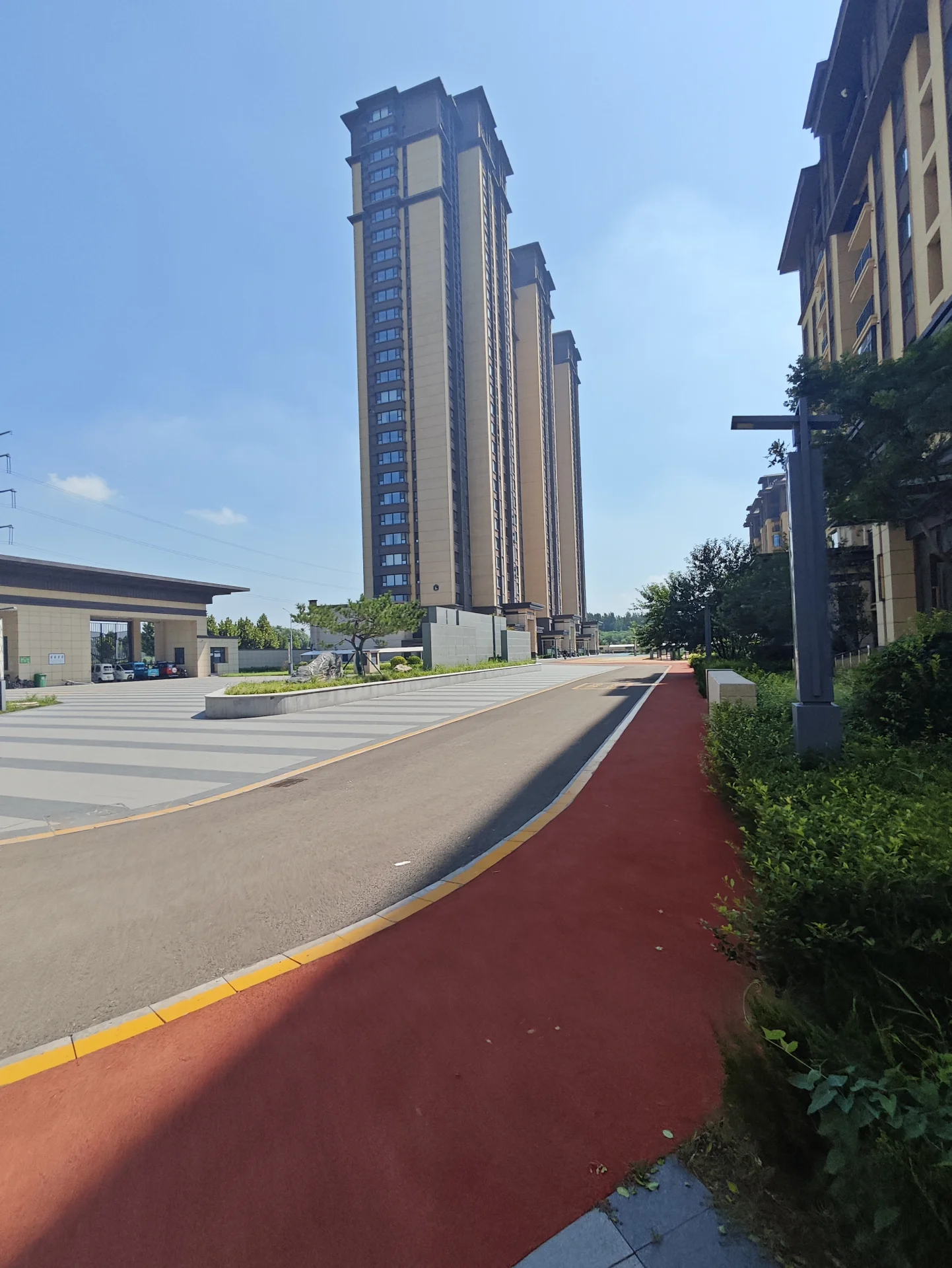 多栋高层住宅的外部立面清晰可见，建筑风格现代，立面材质以浅色调为主，周围有绿化带和街道，整体呈现出城市居住环境的景象。
