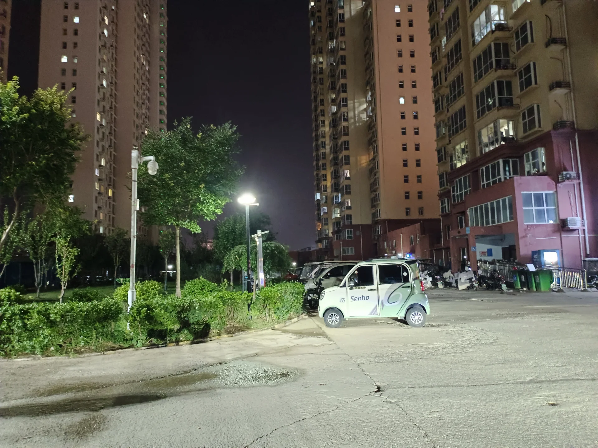 多栋高层住宅楼的夜景，展示了建筑的立面和外墙材质，周边有绿化带和社区道路，整体氛围宁静和谐。
