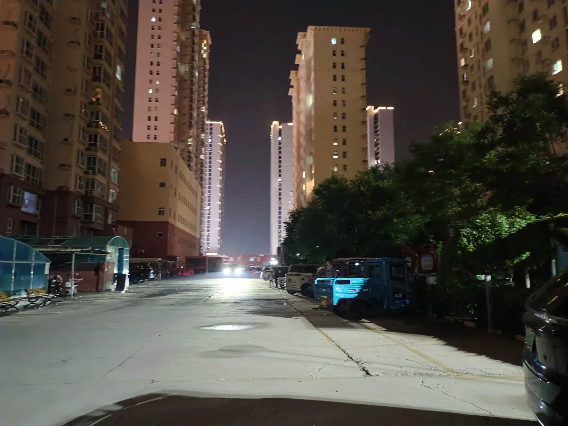 多栋高层住宅楼在夜晚的城市街道上，建筑立面清晰可见，街道上有车辆行驶，整体呈现出繁华而宁静的城市夜景氛围。