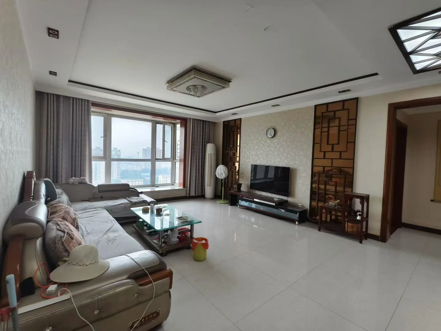 客厅场景，墙面采用浅色调，配有大型沙发和平板电视。采光良好，整体呈现现代简约装修风格，氛围整洁舒适。