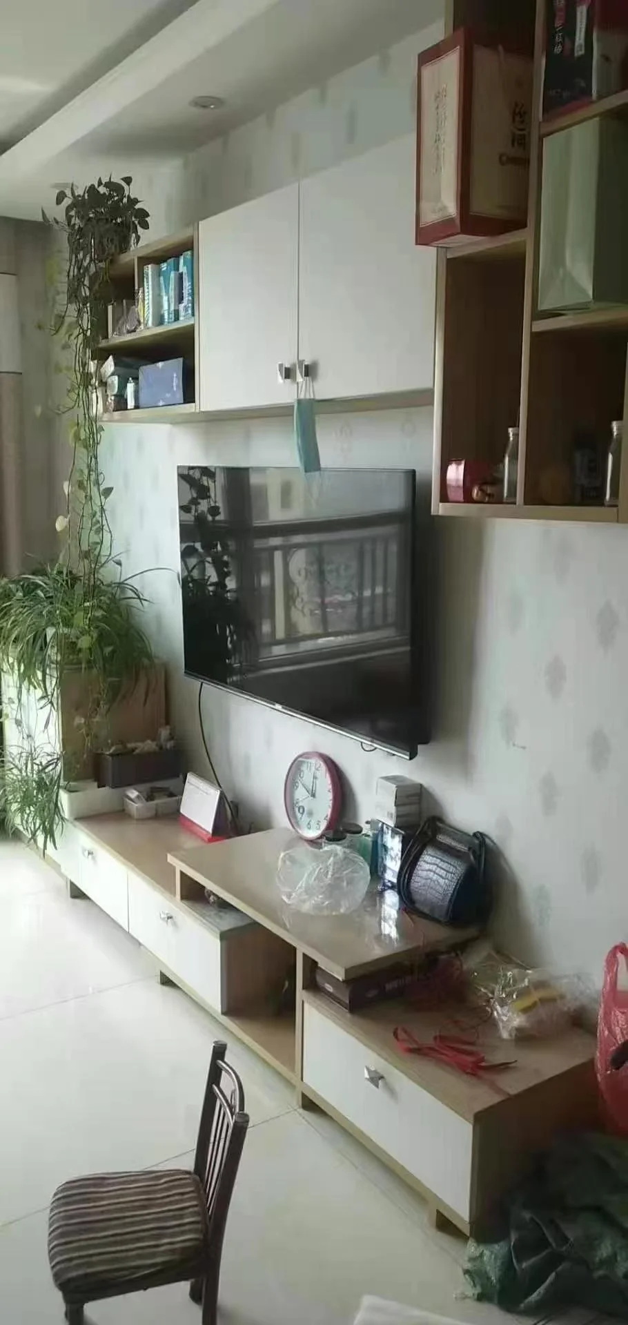 一个现代简约风格的室内空间，墙面为白色，配有多层木质储物柜和电视。空间布局合理，采光良好，整体呈现整洁舒适的居住氛围。