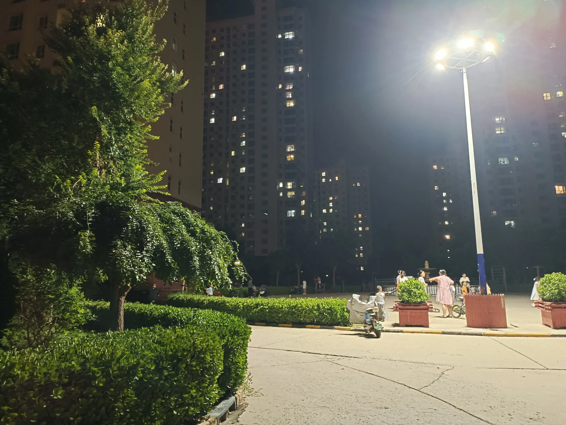 高层住宅楼的外部立面清晰可见，建筑群背景中点缀着茂密的绿化带和街道照明设施，整体呈现出城市社区的宁静与秩序感。