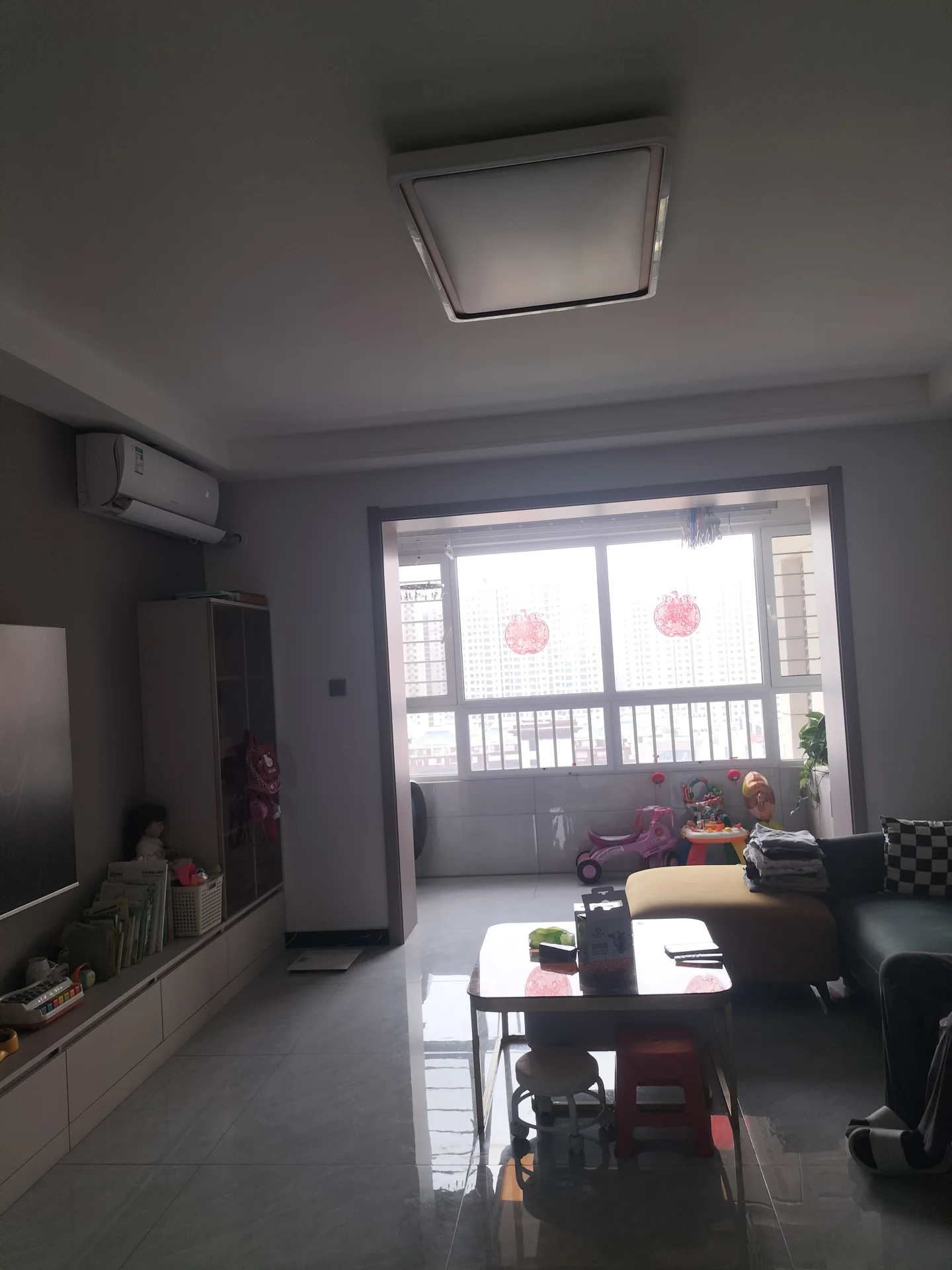 客厅场景，墙面采用浅色调，配有大型平板电视和简约沙发。采光良好，整体呈现现代简约装修风格，氛围整洁舒适。