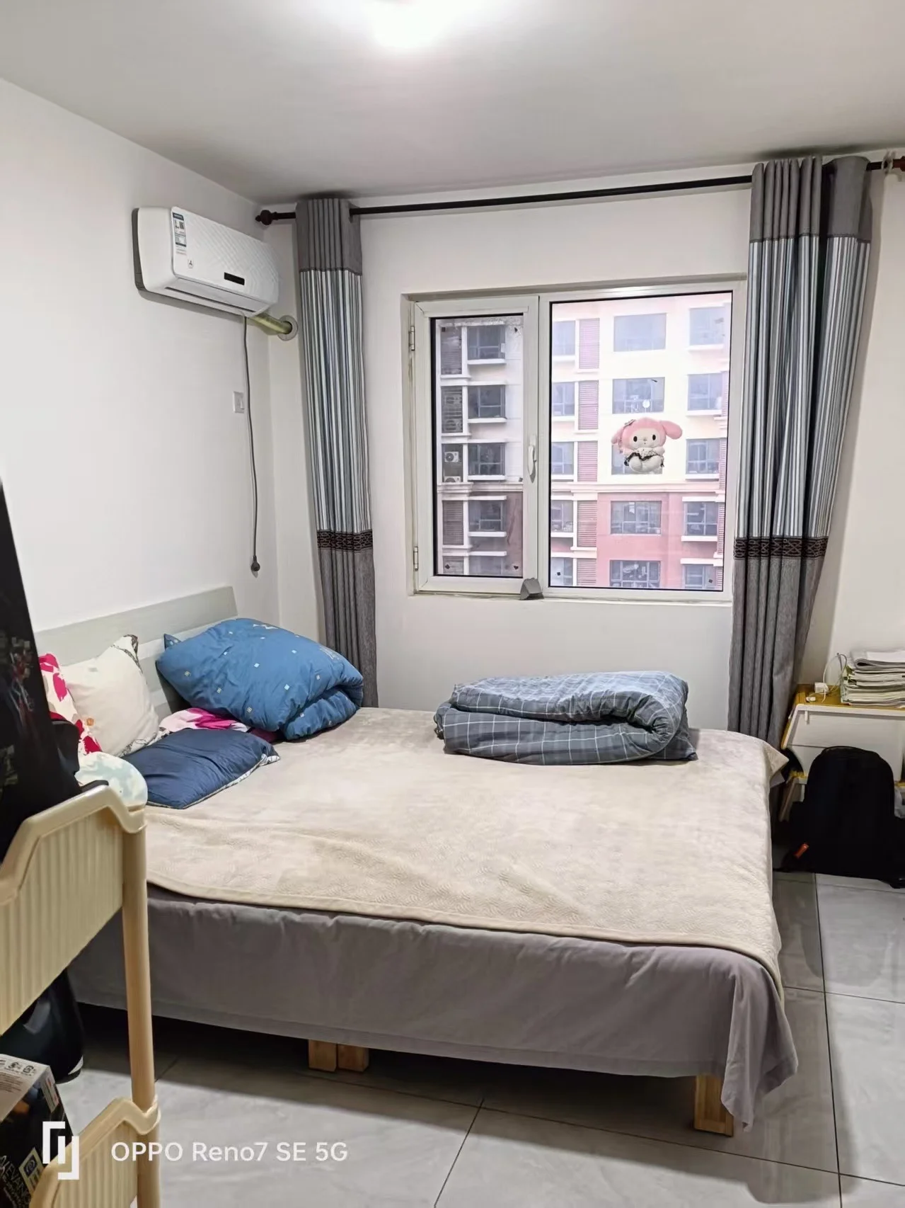 卧室场景，装修风格简洁，配有床铺、床头柜和空调等生活设施。采光良好，整体呈现一个整洁、舒适的居住环境。