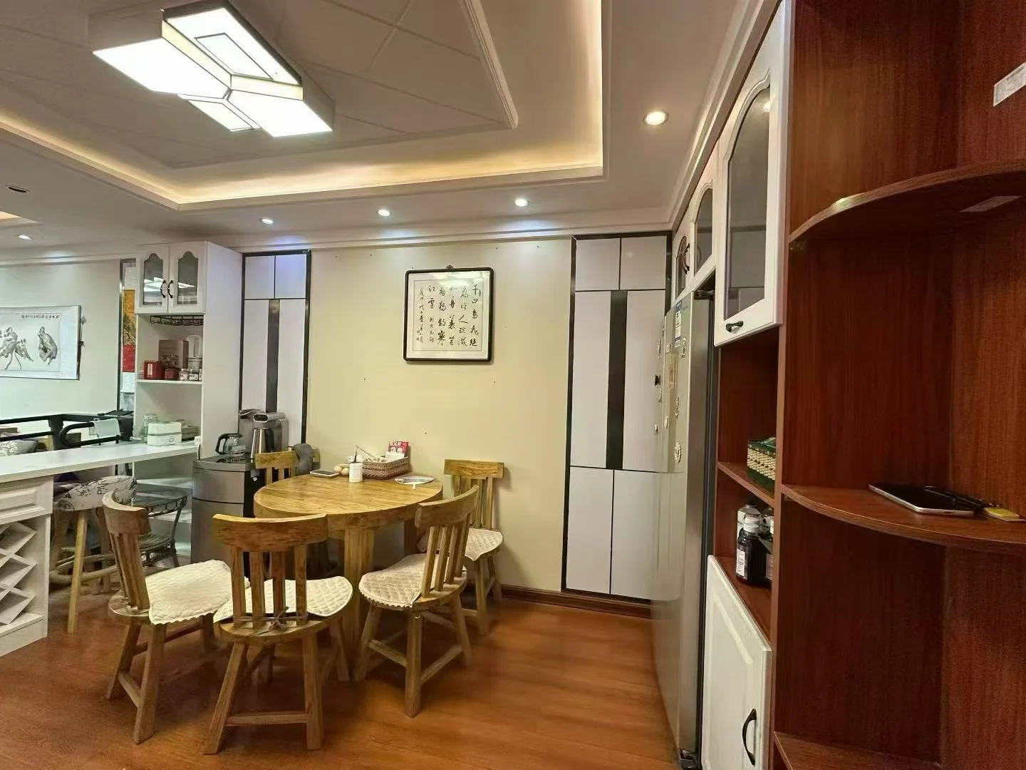 一个宽敞的室内用餐区，装修风格偏向现代简约，配有木质餐桌椅和嵌入式照明。空间采光良好，整体布局整洁舒适，具有温馨的居住氛围。