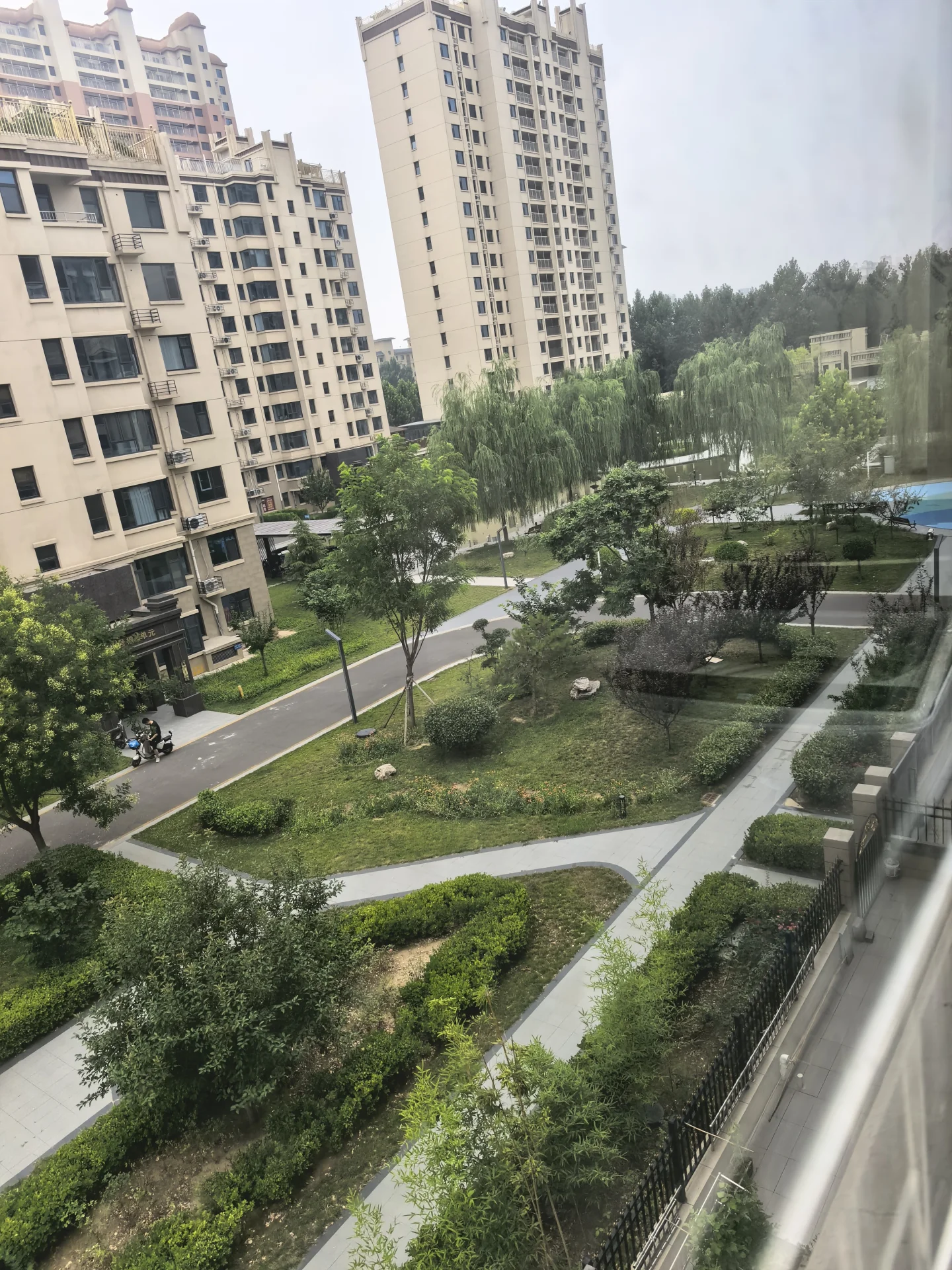 多栋高层住宅的外部立面清晰可见，建筑风格统一，周边绿化带修剪整齐，整体呈现出一种现代、有序的社区居住氛围。