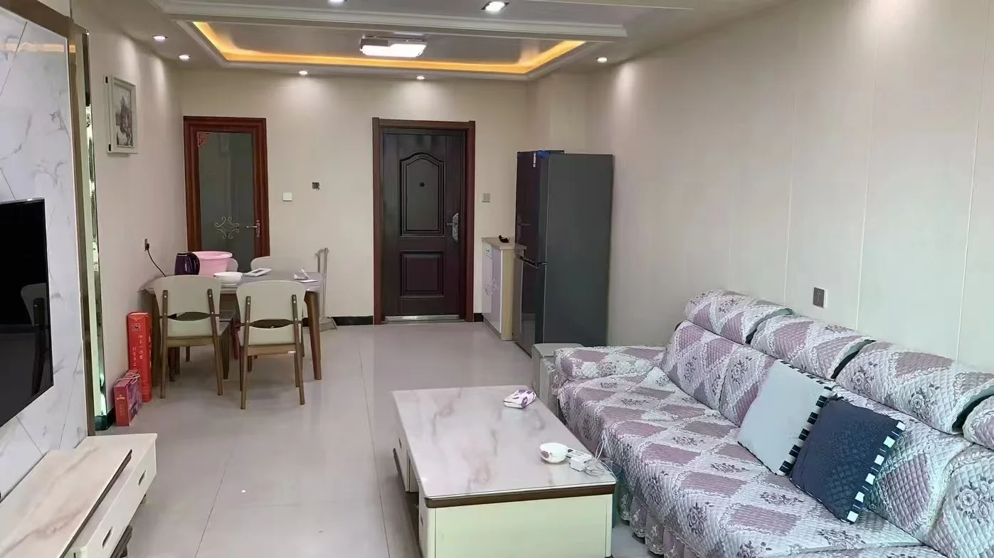 宽敞客厅，有大沙发、餐桌和椅子，墙上有一台电视，家具布局适合放松娱乐，沙发和椅子提供舒适的观影或交谈座位，餐桌和椅子提供额外的用餐或社交空间，氛围温馨宜人。