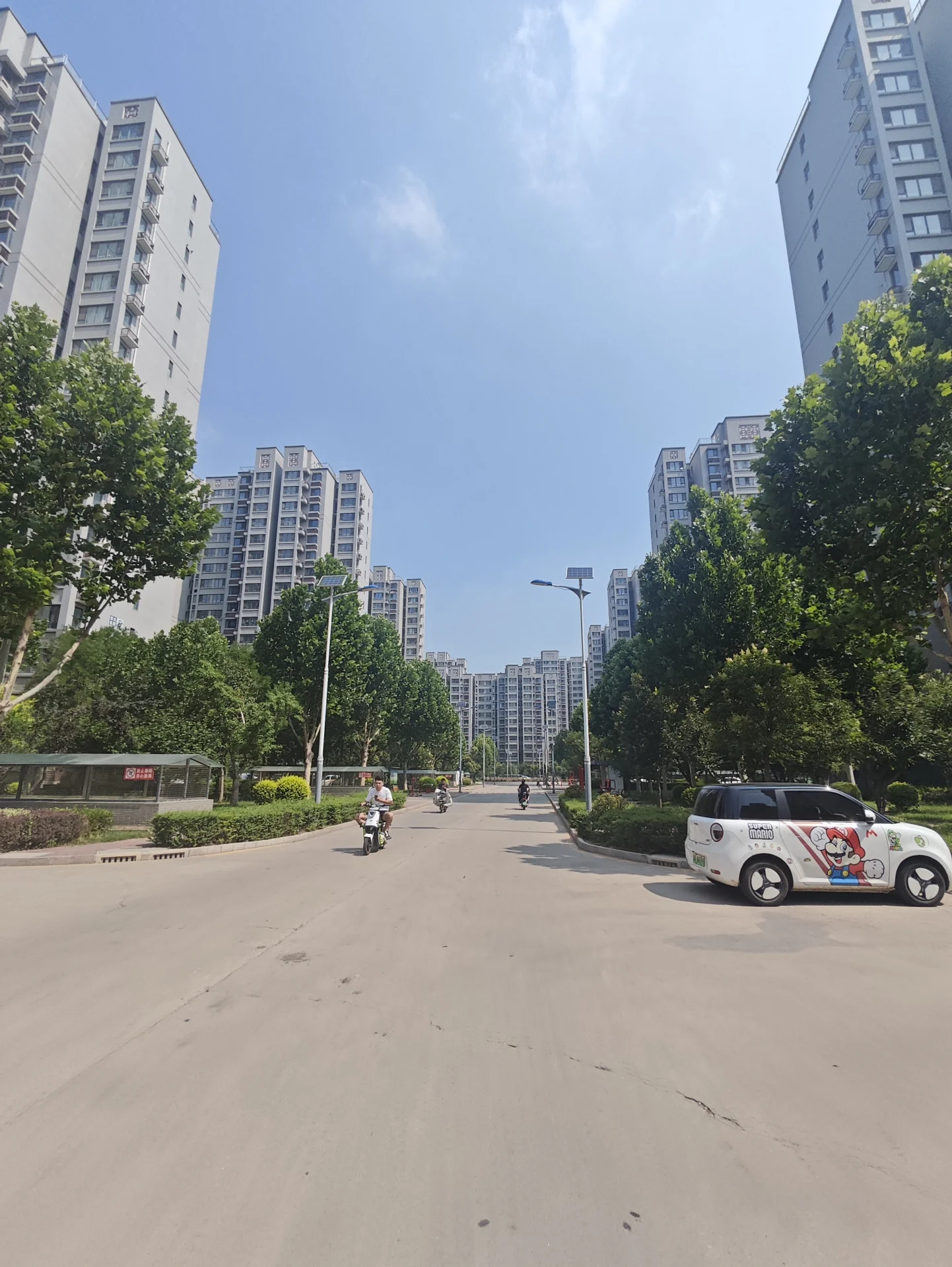 多栋高层白色住宅楼构成了城市景观，街道两旁有茂密的绿化带和树木，整体呈现出宁静、现代的社区建筑外观。